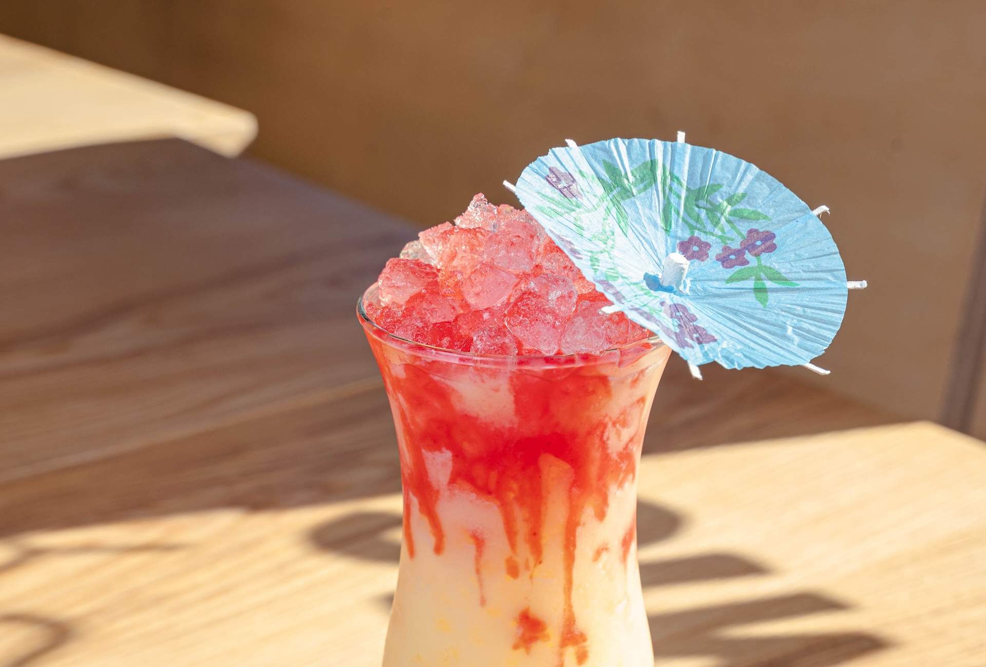 A pink and yellow tropical cocktail with a blue umbrella on top at Los Angeles restaurant All Day Baby