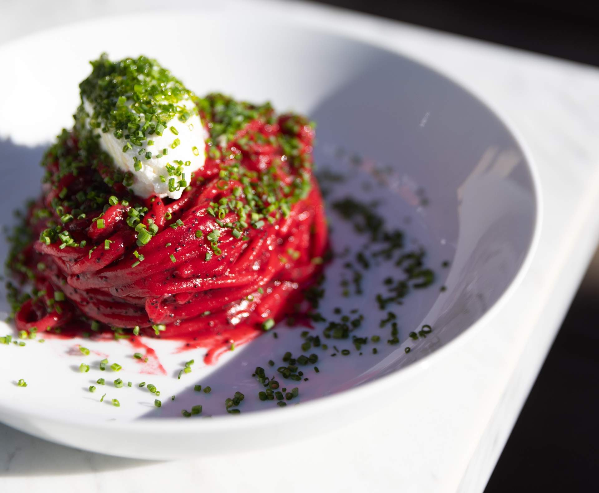 A maroon spaghetti dish with a dollop of cheese on top at Los Angeles restaurant Cento