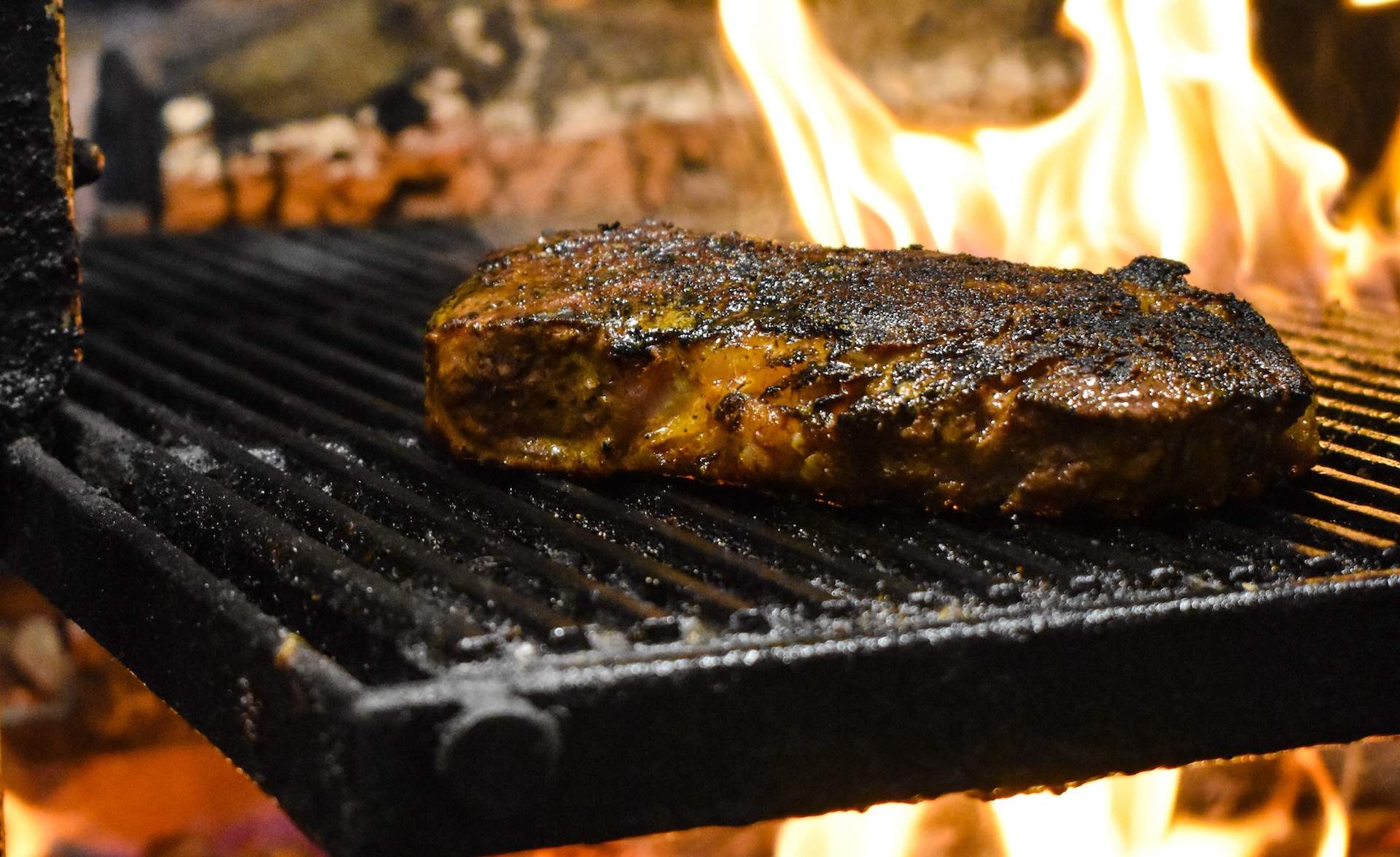 A steak being cooked on an open-fire grill at Los Angeles restaurant Fia Steak