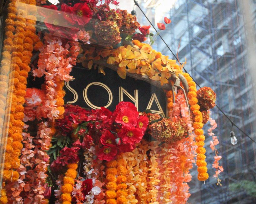 The exterior of NYC Indian restaurant Sona decorated with colorful flower garlands