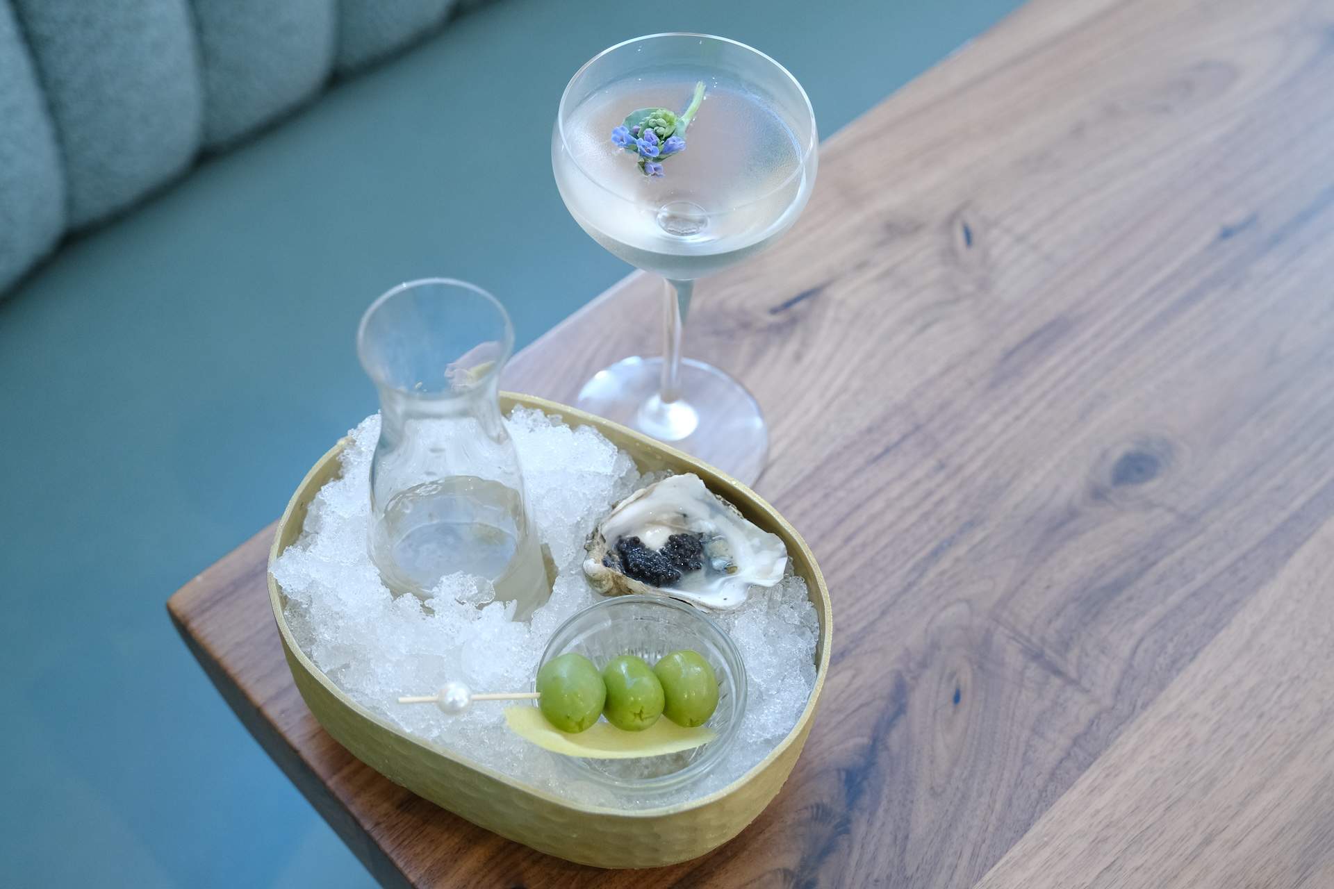 A martini made with roasted oyster shell vodka, housemade vermouth, and salt next to a three-gram caviar bump and a raw oyster at Joyce in Los Angeles