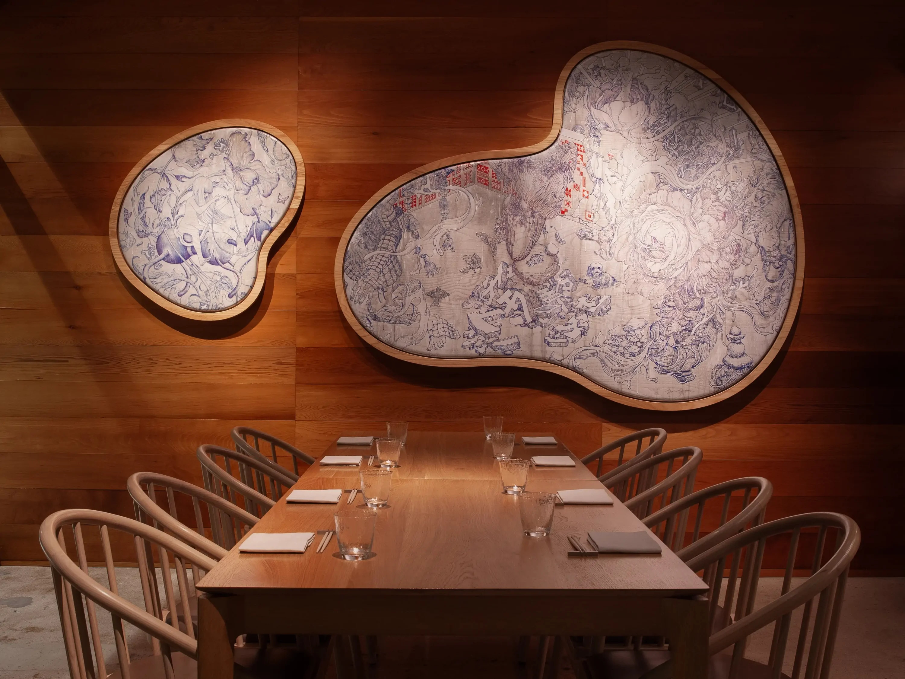 Two blue and white Taiwanese textiles on wooden walls with a wooden table and chairs at Kato, one of the best date night restaurants in Los Angeles. Book on OpenTable.