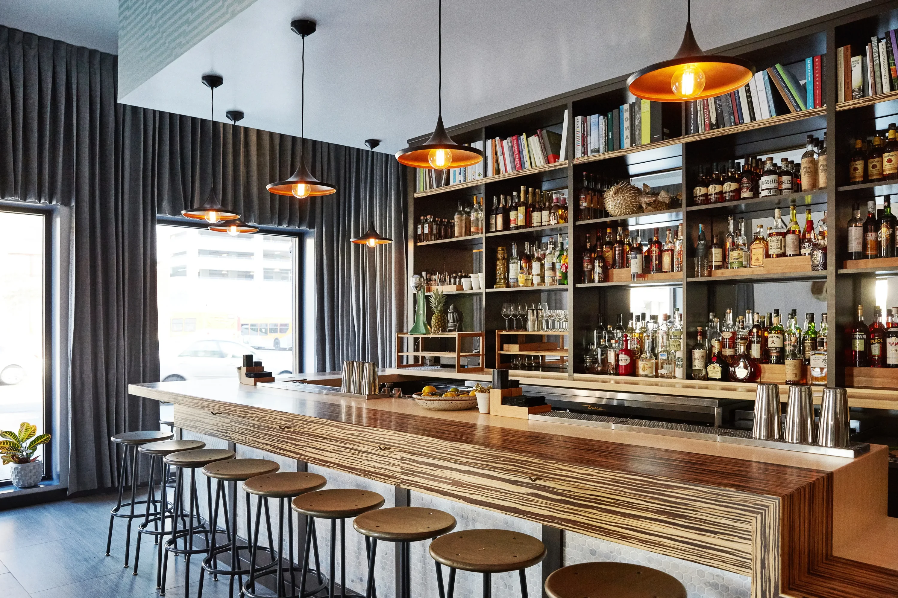 A small bar with stools and gray curtains around windows at Here’s Looking at You in Los Angeles, available on OpenTable.