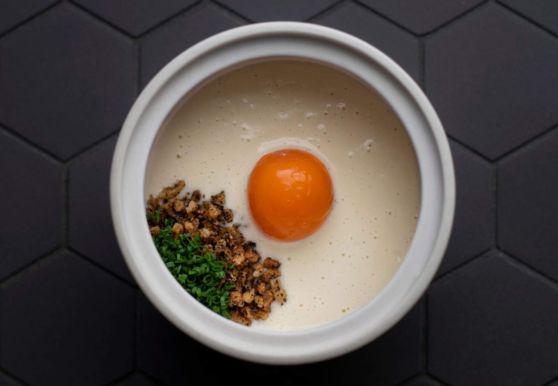 A white sauce dish with an egg yolk peeking out at Oakland restaurant Commis