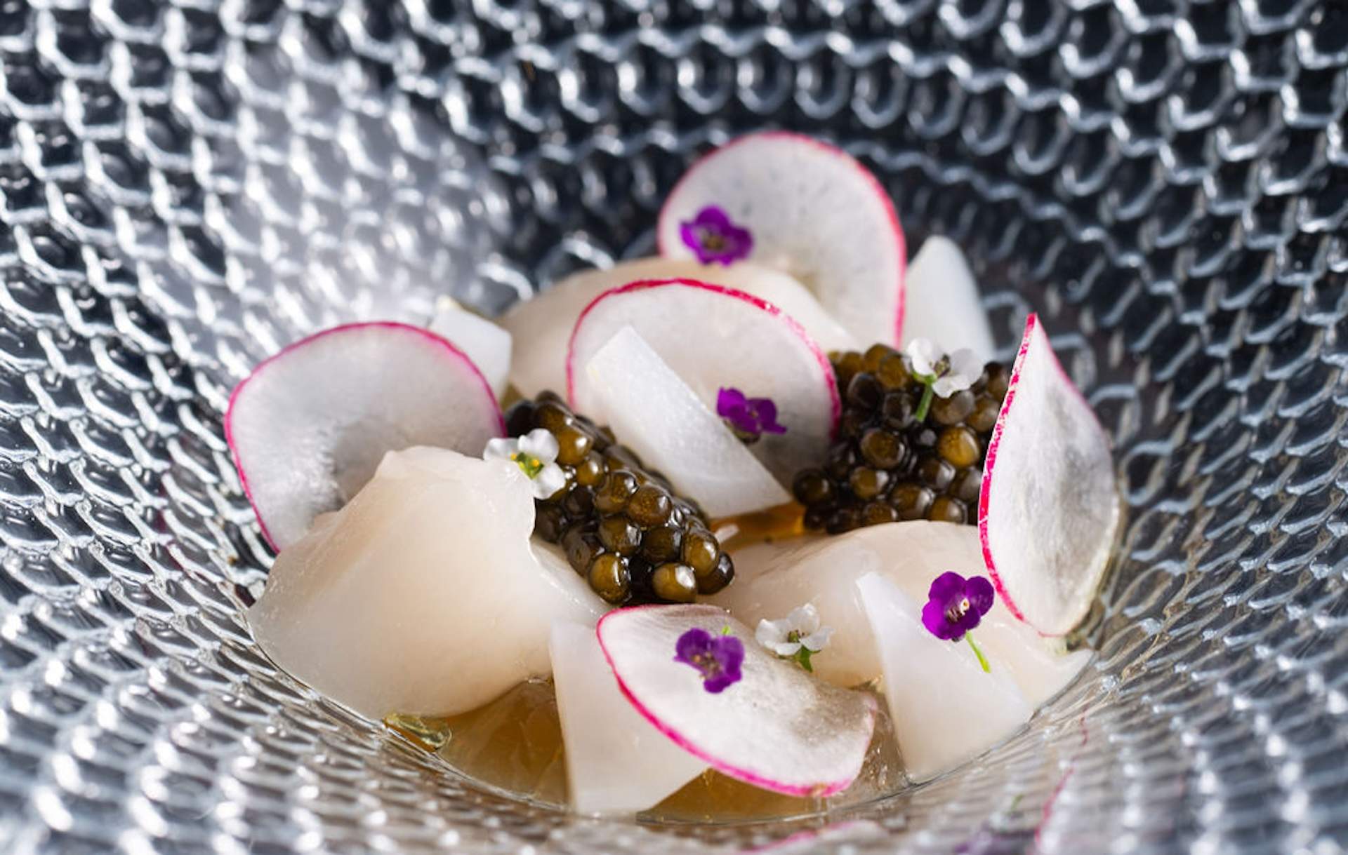 Thinly sliced radishes in a bowl with pieces of white fish and caviar at Oakland restaurant Commis