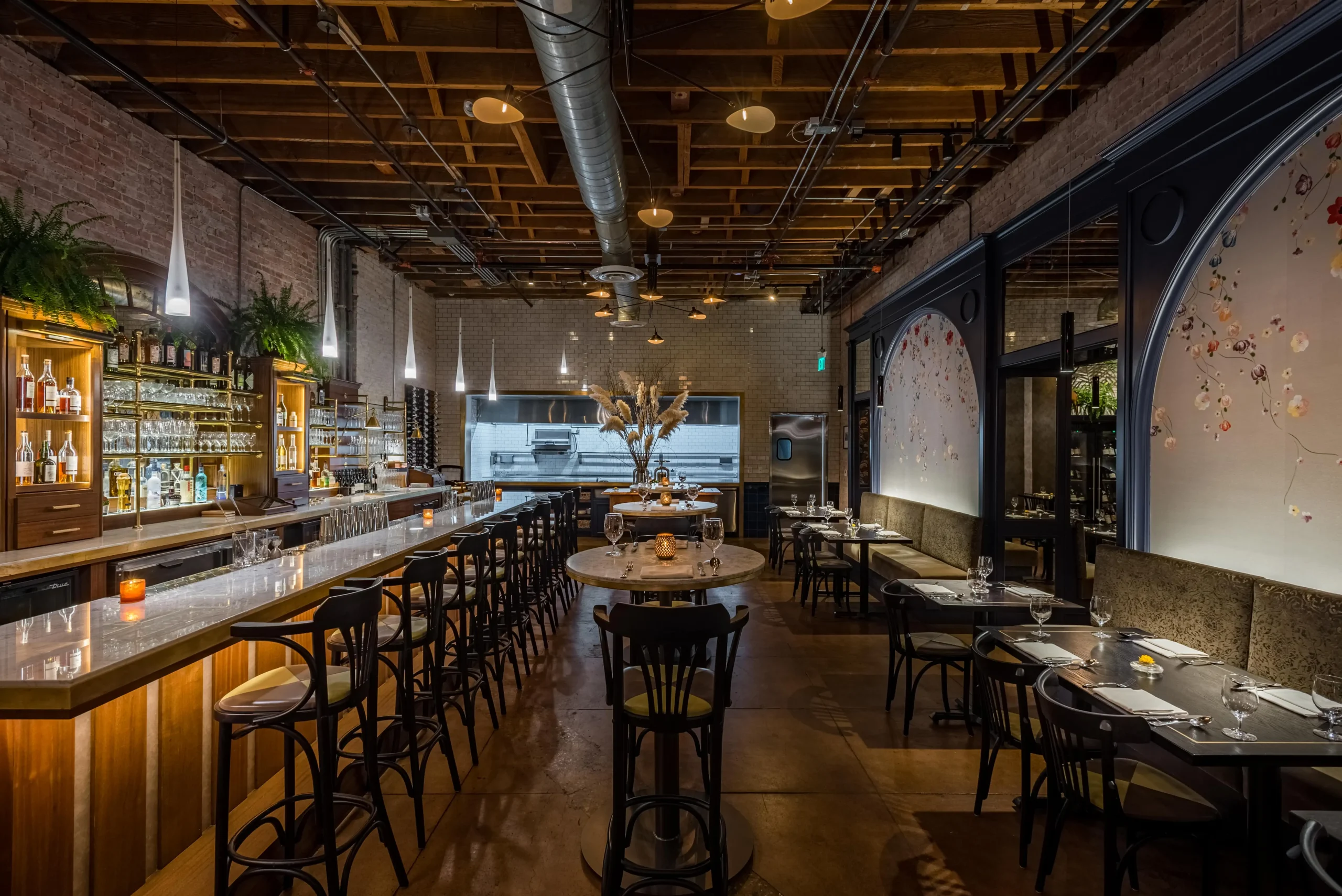 Navy tones, arches adorned with hand-painted floral silk wallpaper from de Gournay, and exposed brick at Pasjoli in Los Angeles