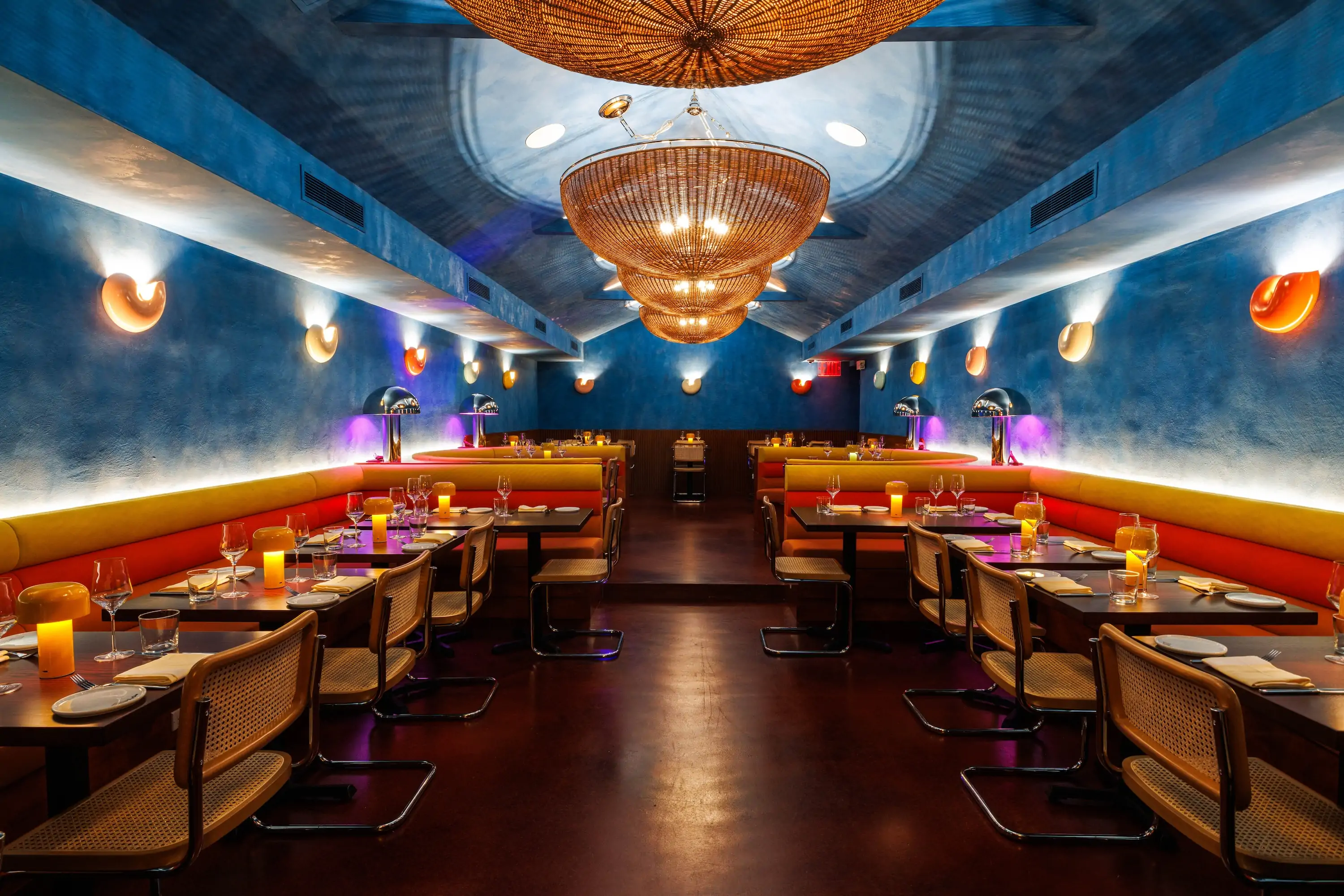 The interior of New York restaurant Il Totano with bright blue ceilings and red couches