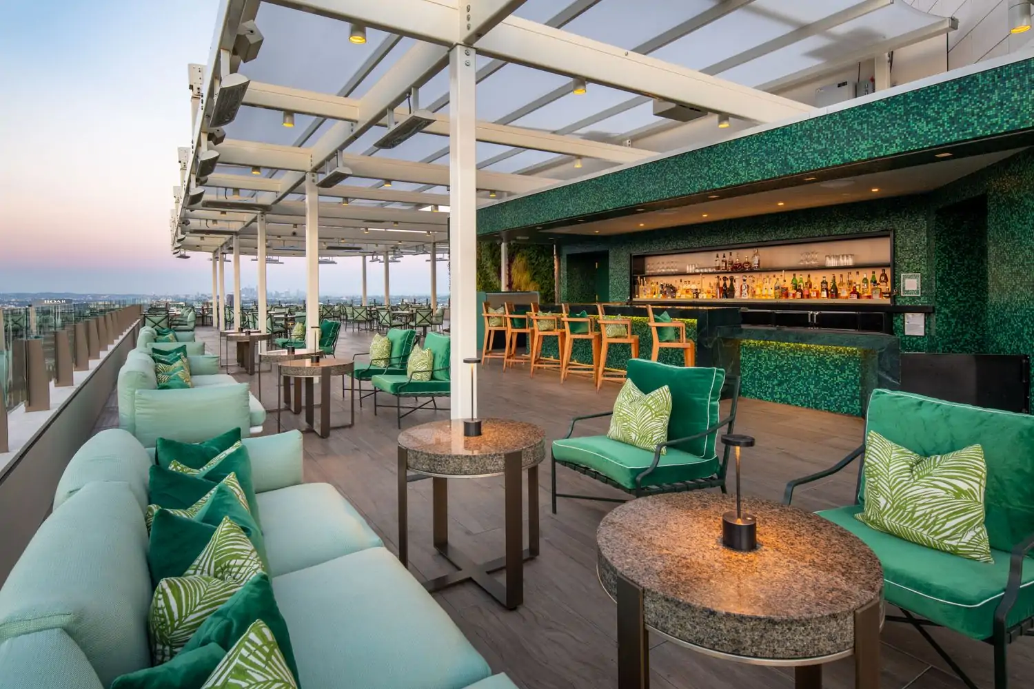 A garden-style terrace with green decor and a fantastic view of Los Angeles at The Rooftop Beverly Hills, one of the best Los Angeles Beverly Hills restaurants.