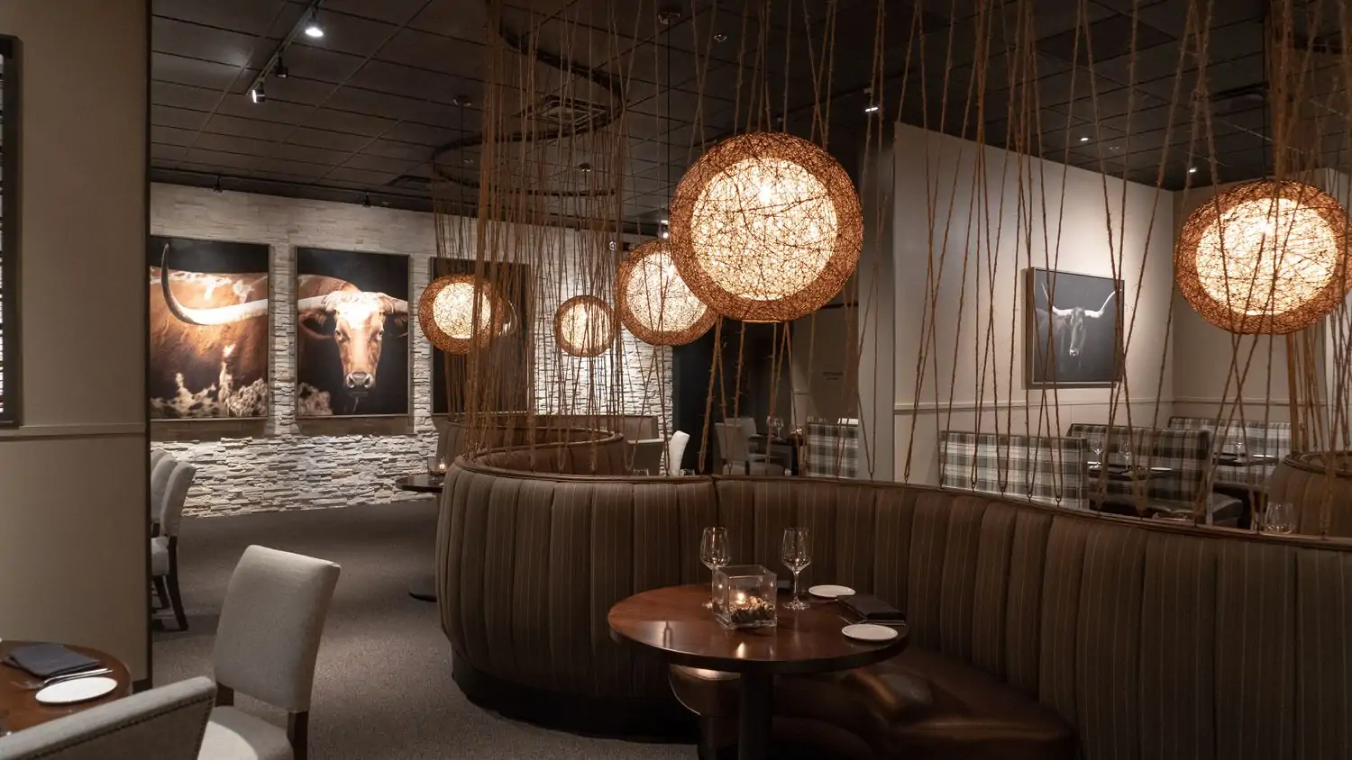 Chevron-patterned wing-back chairs, photos of longhorns, dark curved room divider, and tables at Vince Young Steakhouse, one of the nice restaurants in Austin. Book on OpenTable.