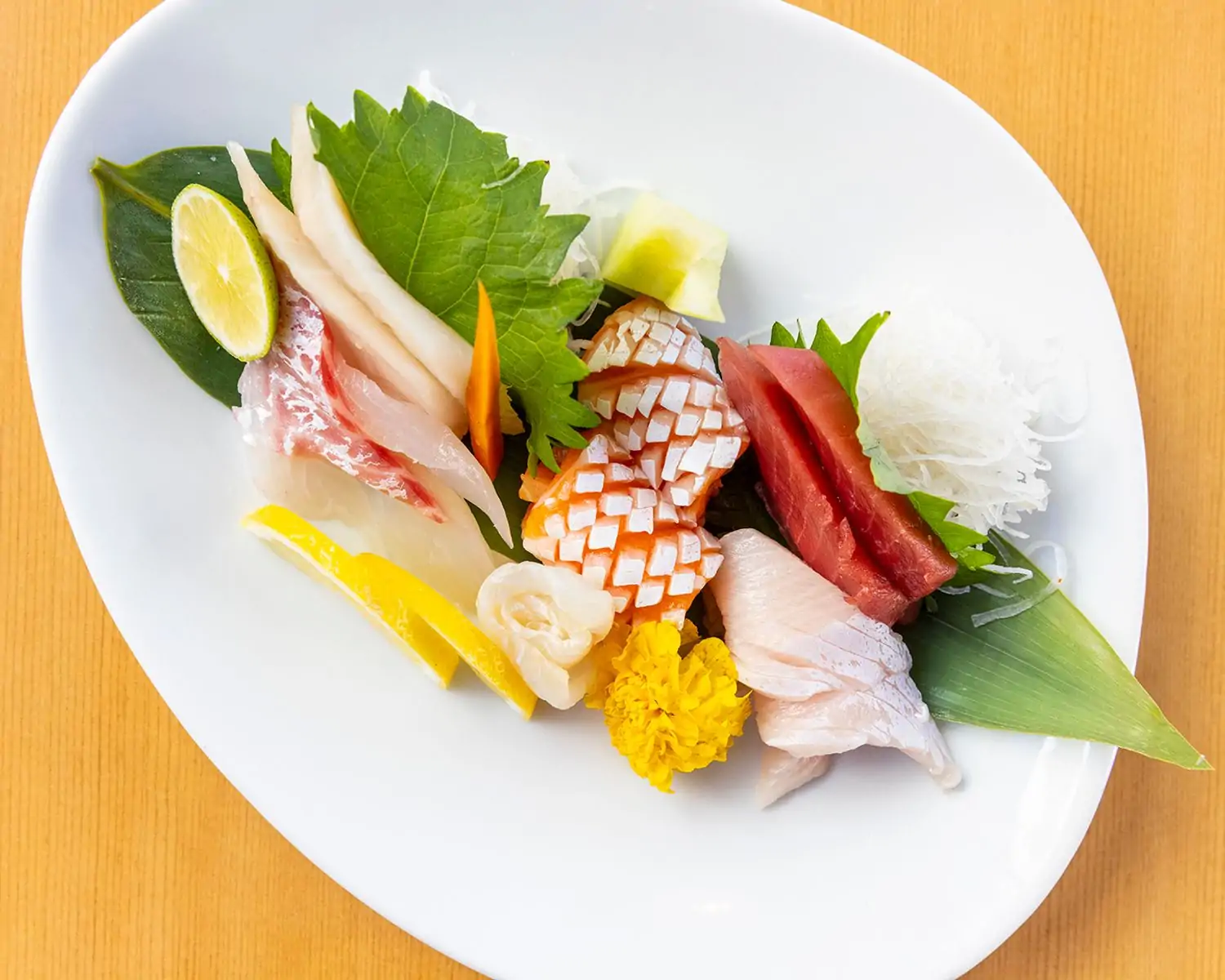 A plate featuring fresh veggies and raw fish presented with slices of lemon at Kombu Sushi & Sake, one of the best Little Tokyo Los Angeles restaurants. Book on OpenTable.