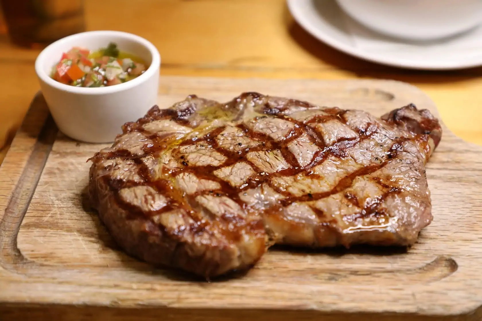 A large piece of steak on a white plate at NYC restaurant Porteño