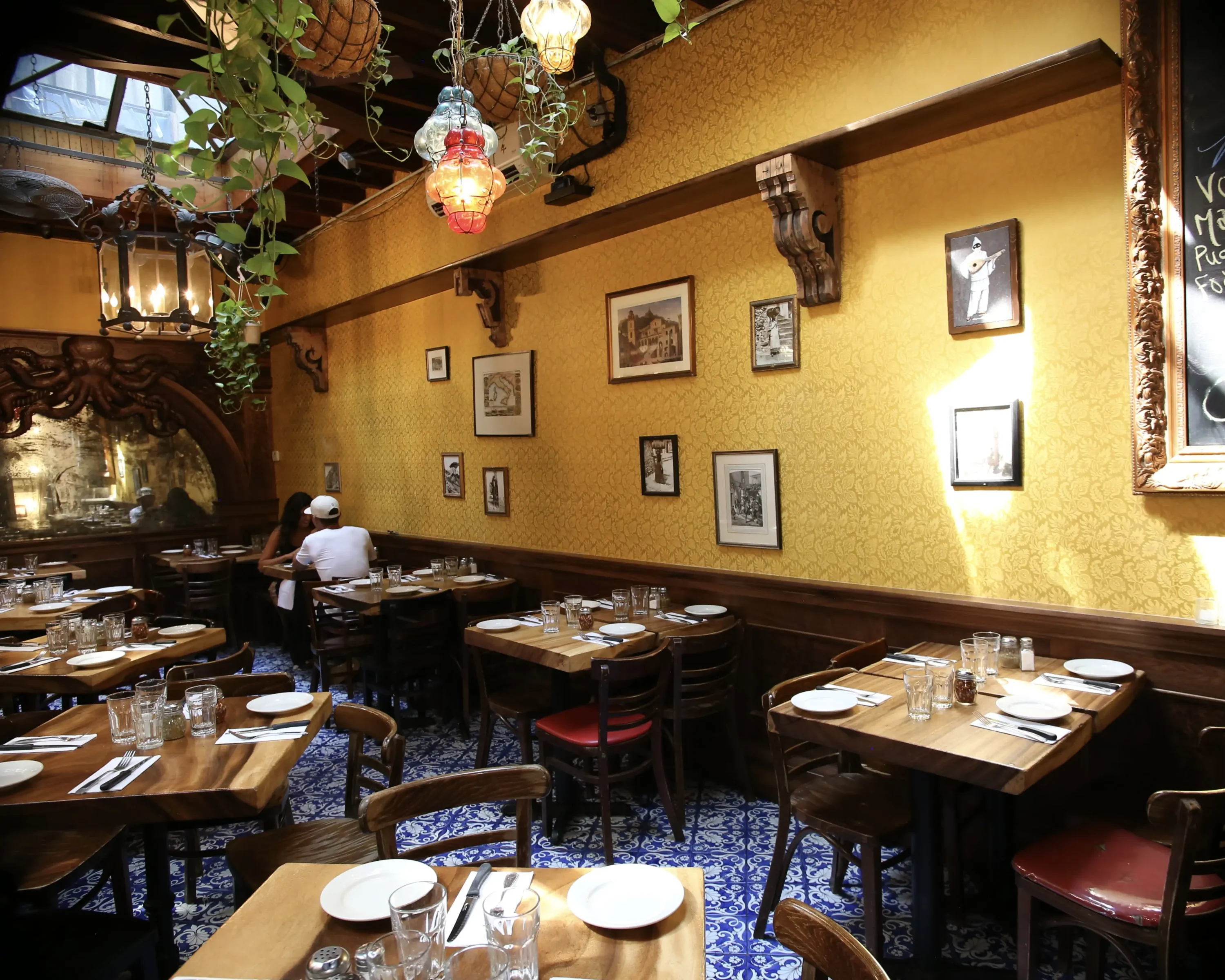 Gold wallpaper, blue tile, and plants in the dining room at Lil' Frankie's, one of the best Italian restaurants in New York City. Book on OpenTable.