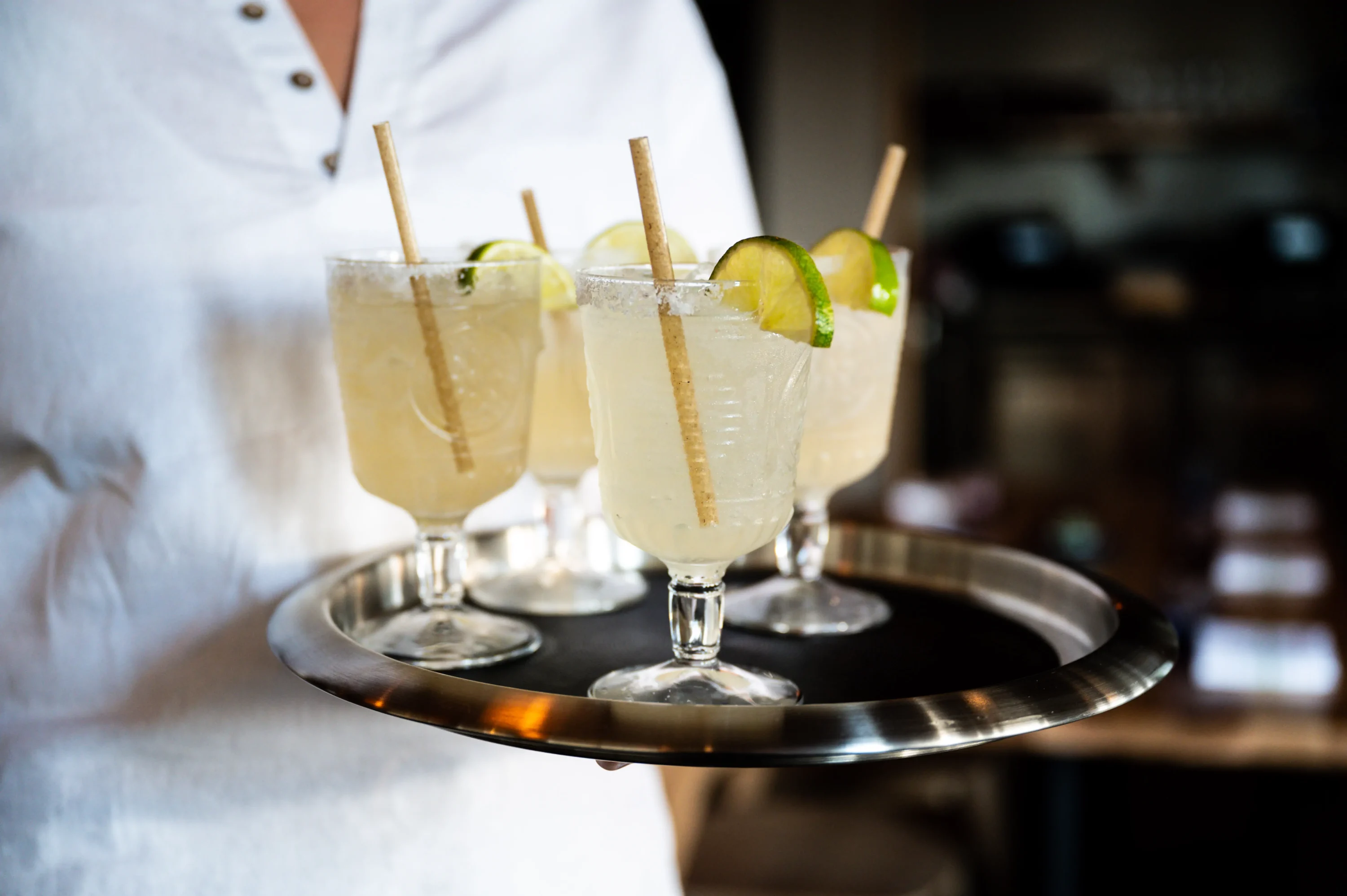 A server holds a tray of margaritas with salt rims and lime garnishes at Bulevar Mexican Kitchen in Austin. Book on OpenTable.