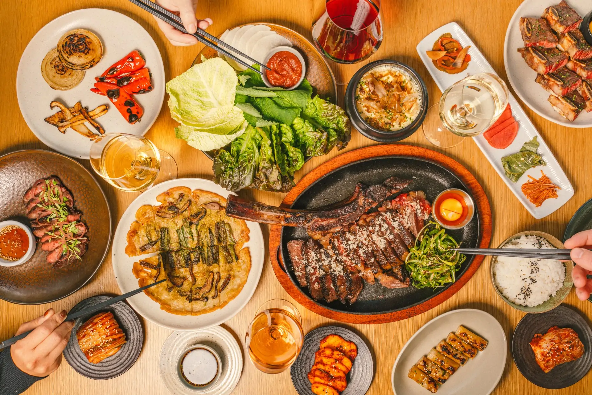 A table with plates of kimchi, pancakes, wagyu hanger steak, rice, and wine glasses at Underdog, one of the fancy restaurants in Austin.