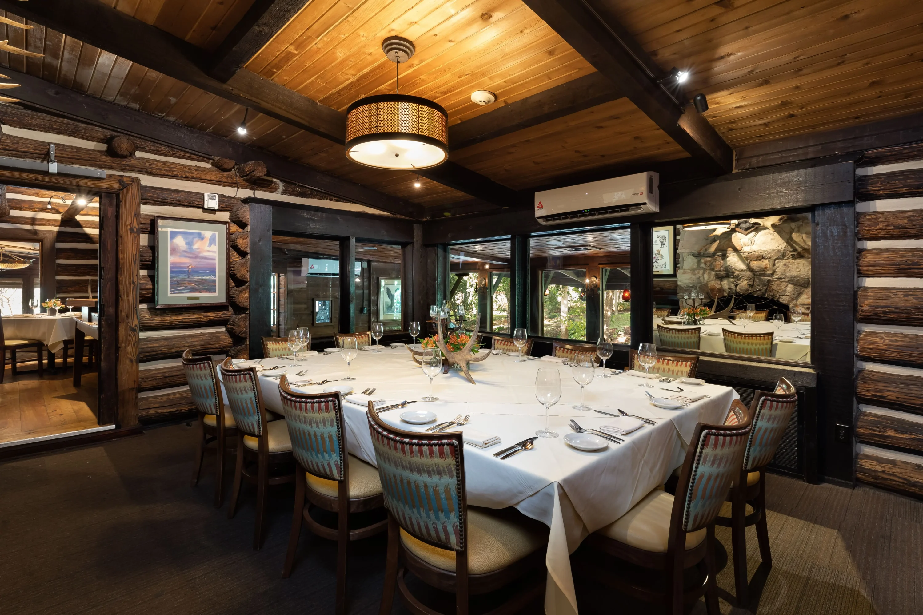 A table and chairs in a wood-lined dining room with windows at The Rainbow Lodge in Houston. Book on OpenTable.