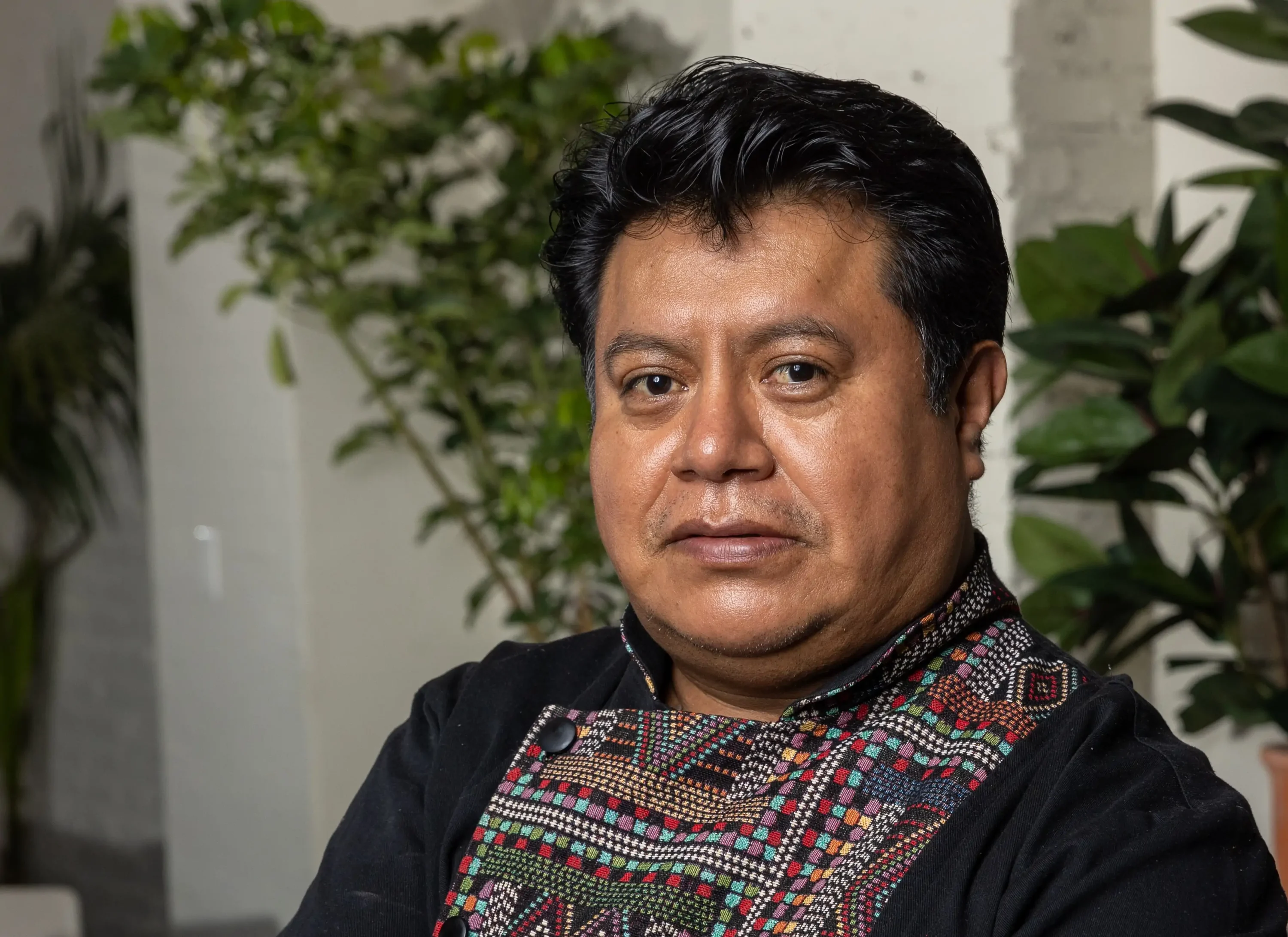 The chef of NYC restaurant Casa Bond in a black patterned shirt standing in his restaurant