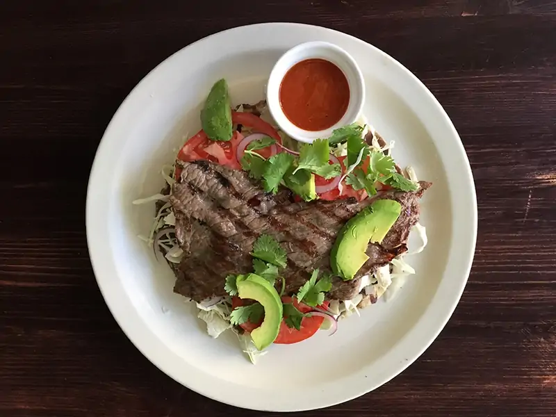 Steak on top of tortilla with tomatoes and shredded lettuce at Chicago restaurant Kie-Gol-Lanee