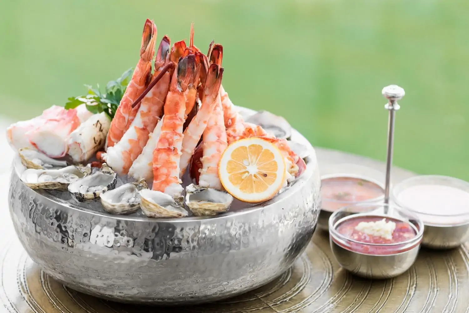 A metal bowl with ice chills fresh shrimp tails, raw oysters, and crab legs, while three small condiment dishes rest on the table at Gibsons Italia, one of the best Italian restaurants in Chicago. Available on OpenTable.