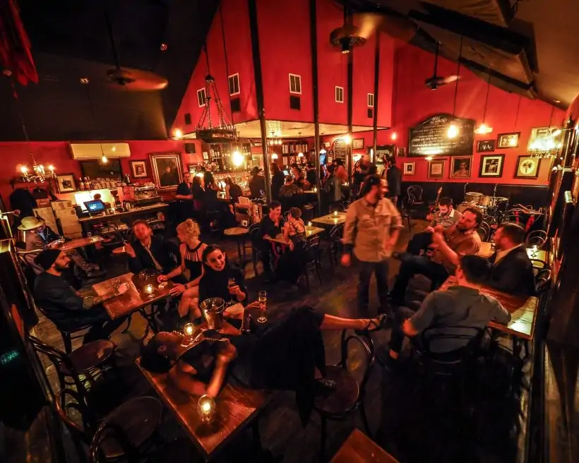 Diners in a dark room with red walls and photographs on the wall at Justine’s Brasserie in Austin. Book on OpenTable.