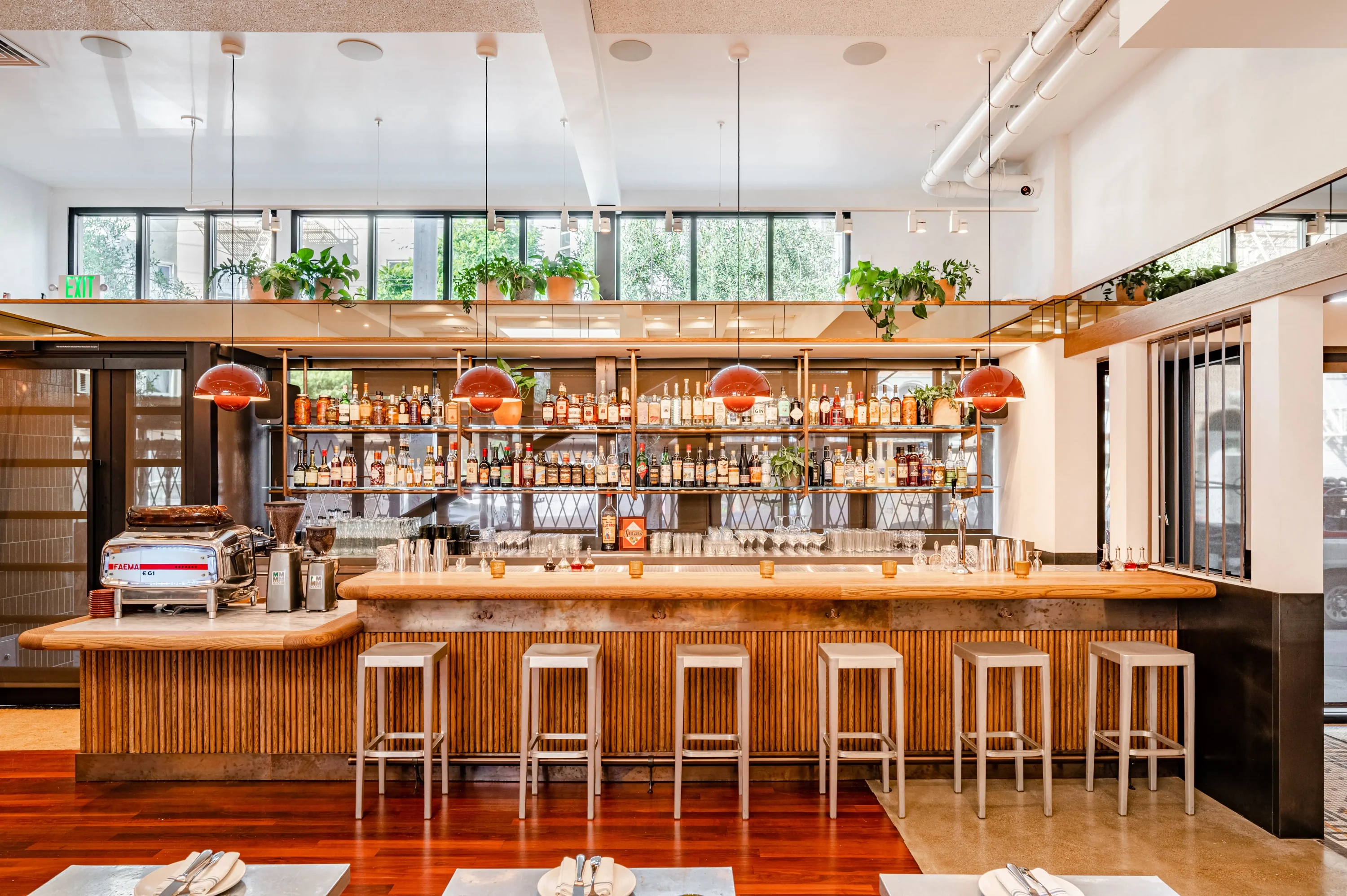 A bright room with white ceilings and a trendy light wood bar at Delfina Restaurant, one of the best Italian restaurants in San Francisco.
