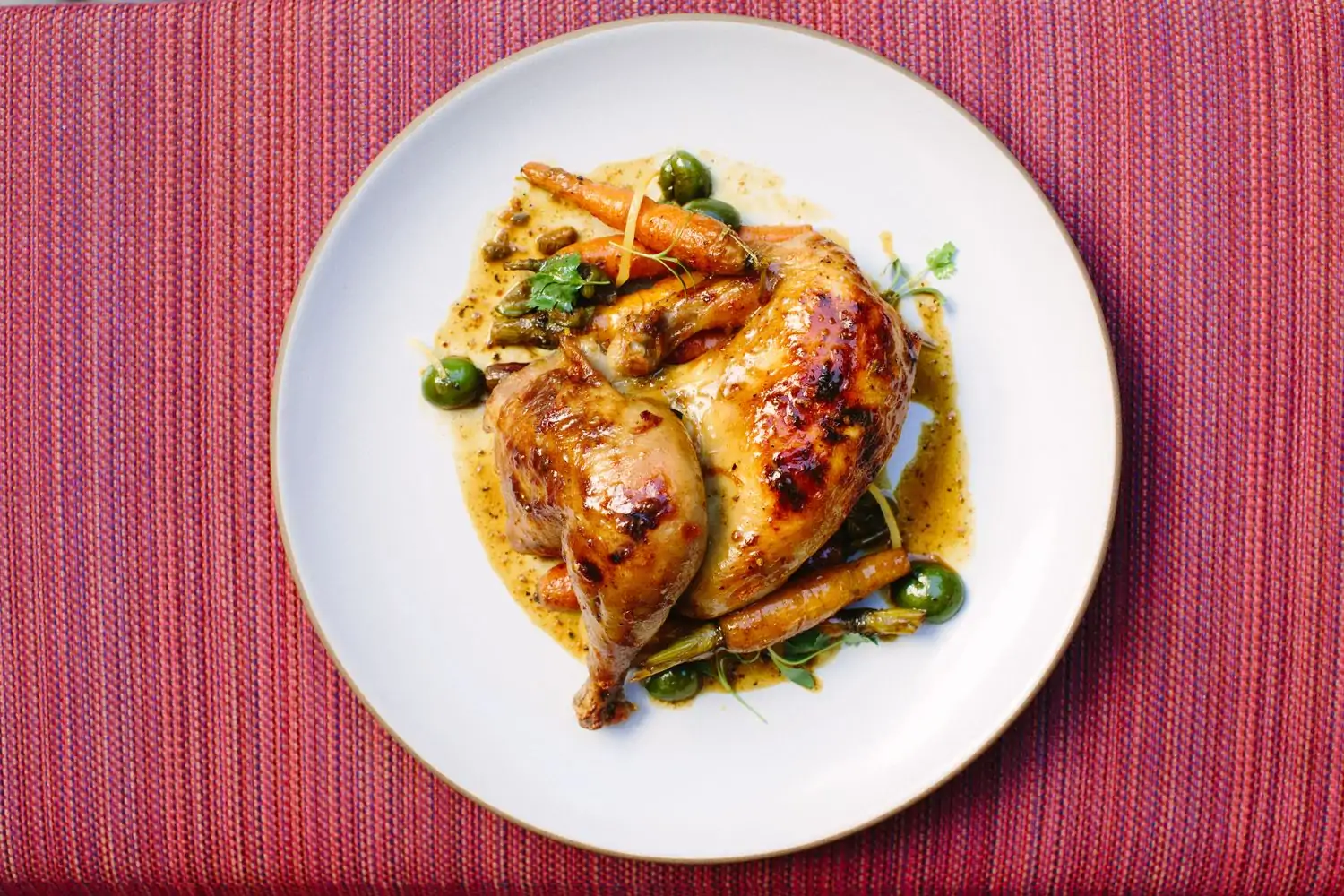 A plate with roasted chicken thighs in sauce with carrots and other garnishes at Redbird, one of the best American restaurants in Los Angeles, CA, found on OpenTable.