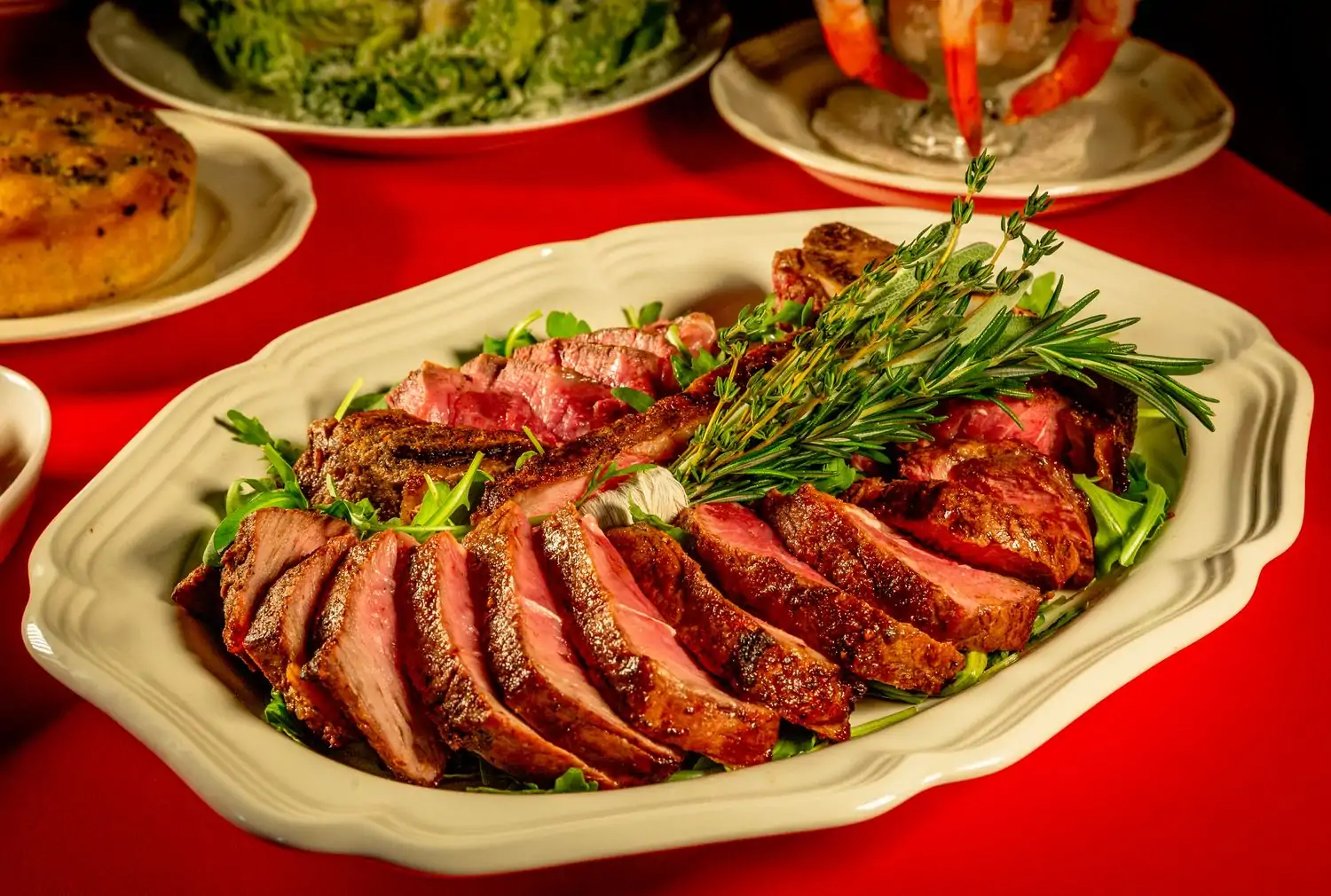 A white platter laden with bistecca alla Fiorentina served atop a bed of fresh greens with a rosemary garnish at The Red Fox, in Boston, on OpenTable.