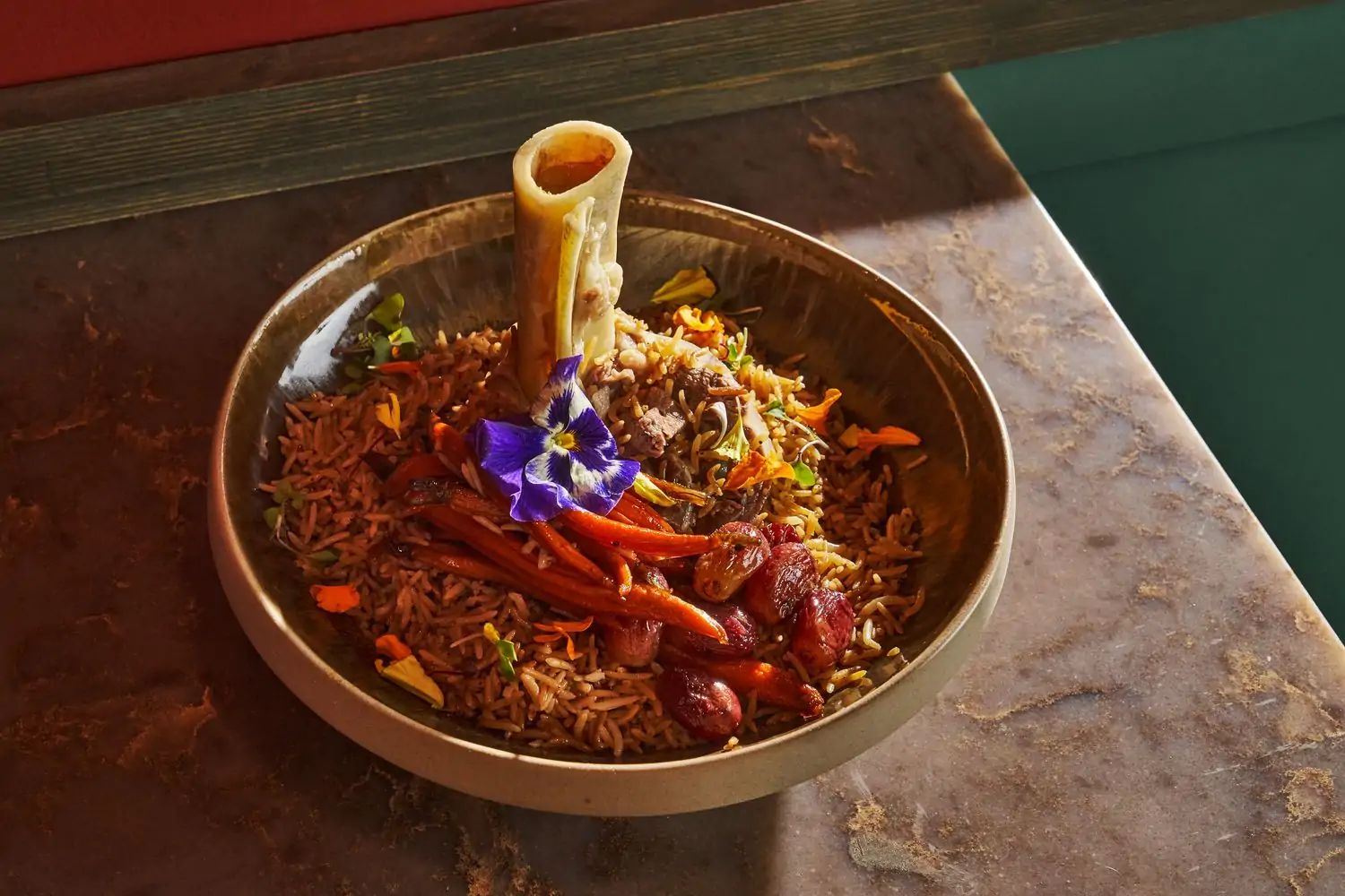 A ceramic bowl of biryani with a decorative purple flower at Shor, one of the best Indian restaurants in Los Angeles, available on Open Table.