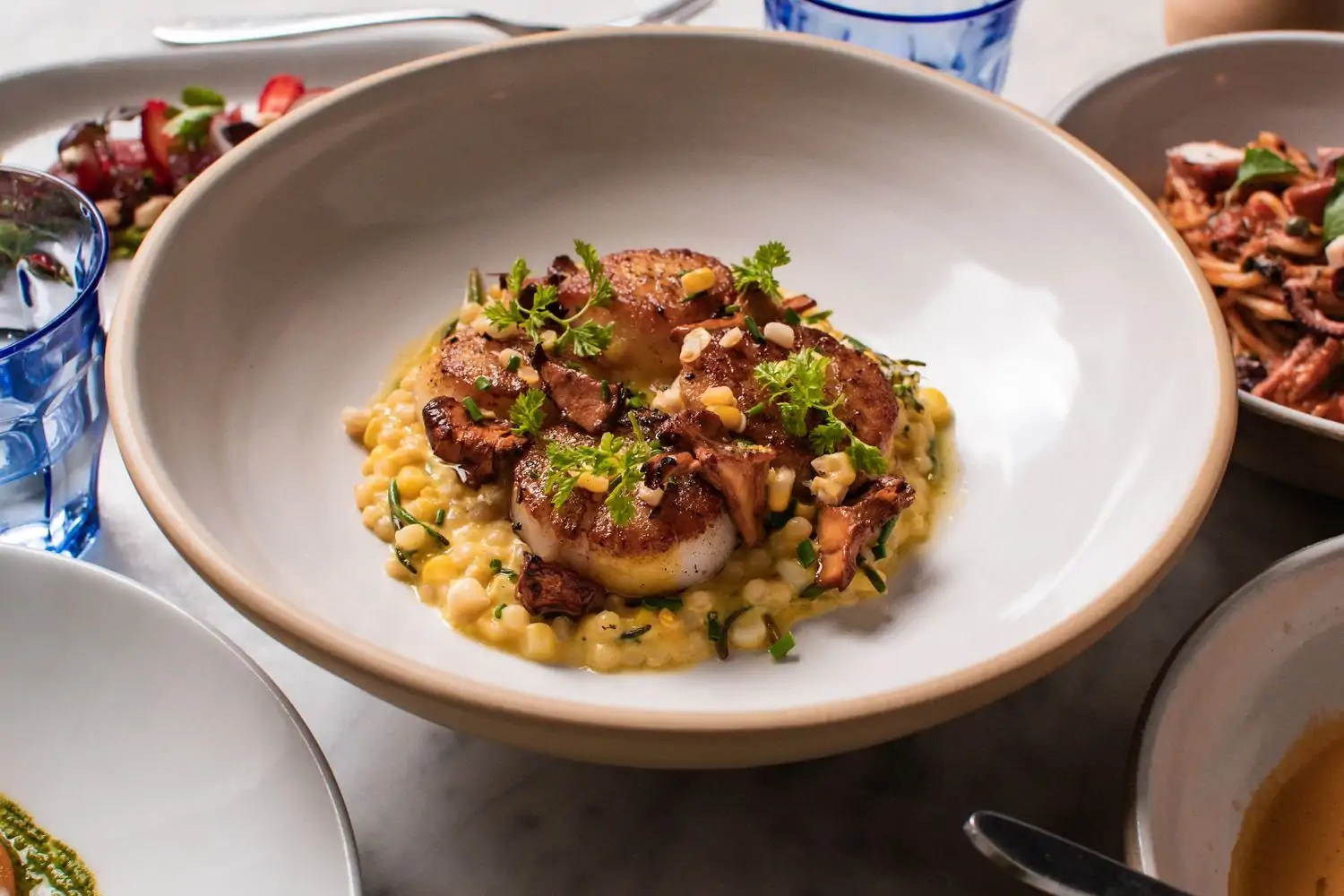 Scallops alla plancha atop a bed of spiced couscous and corn with parsley garnishes at Porto, one of the Boston best Italian restaurants on OpenTable.