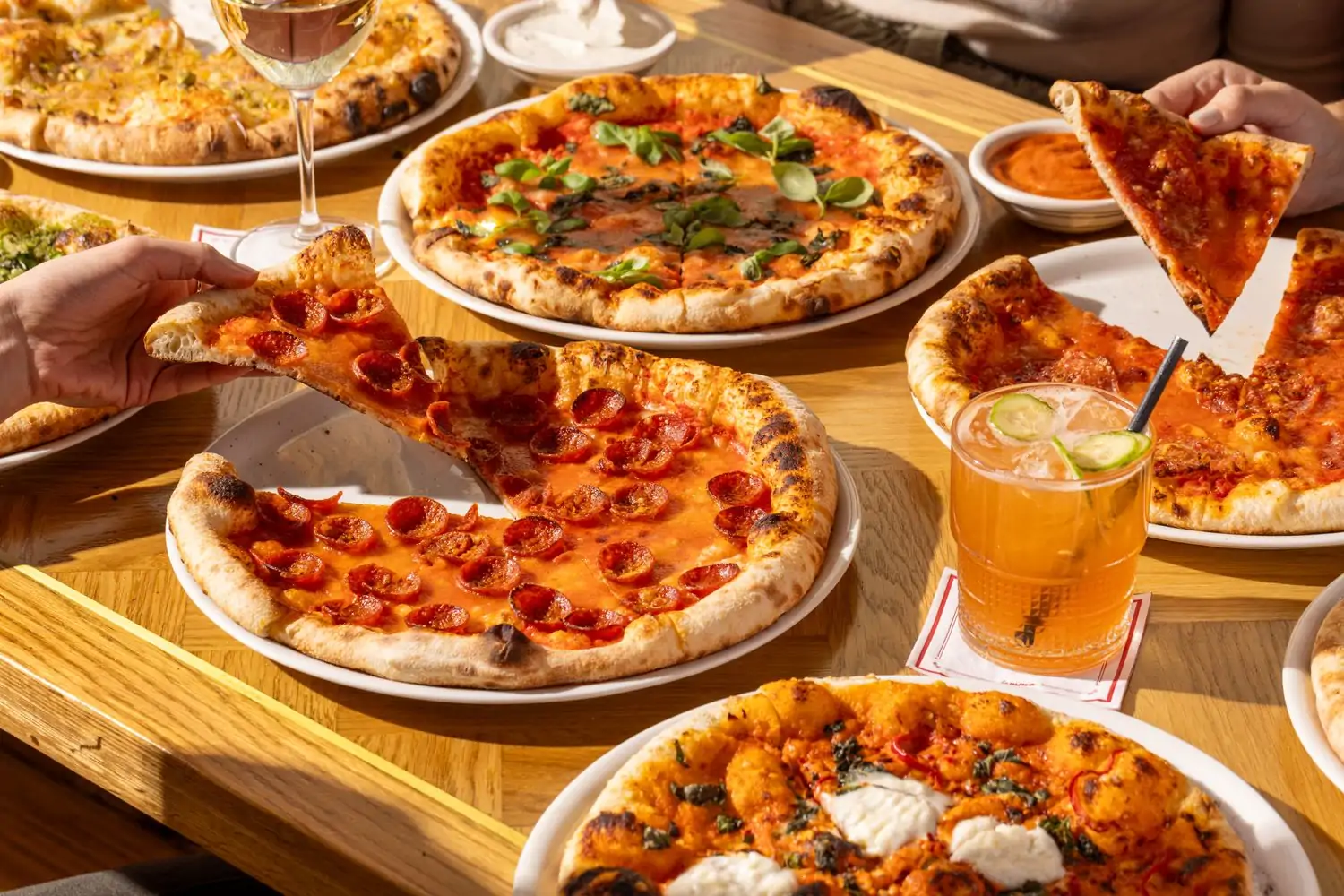 A large, long table with different pizzas with different ingredients at Jemma, one of the best restaurants in Los Angeles Hollywood, you can reserve on OpenTable.