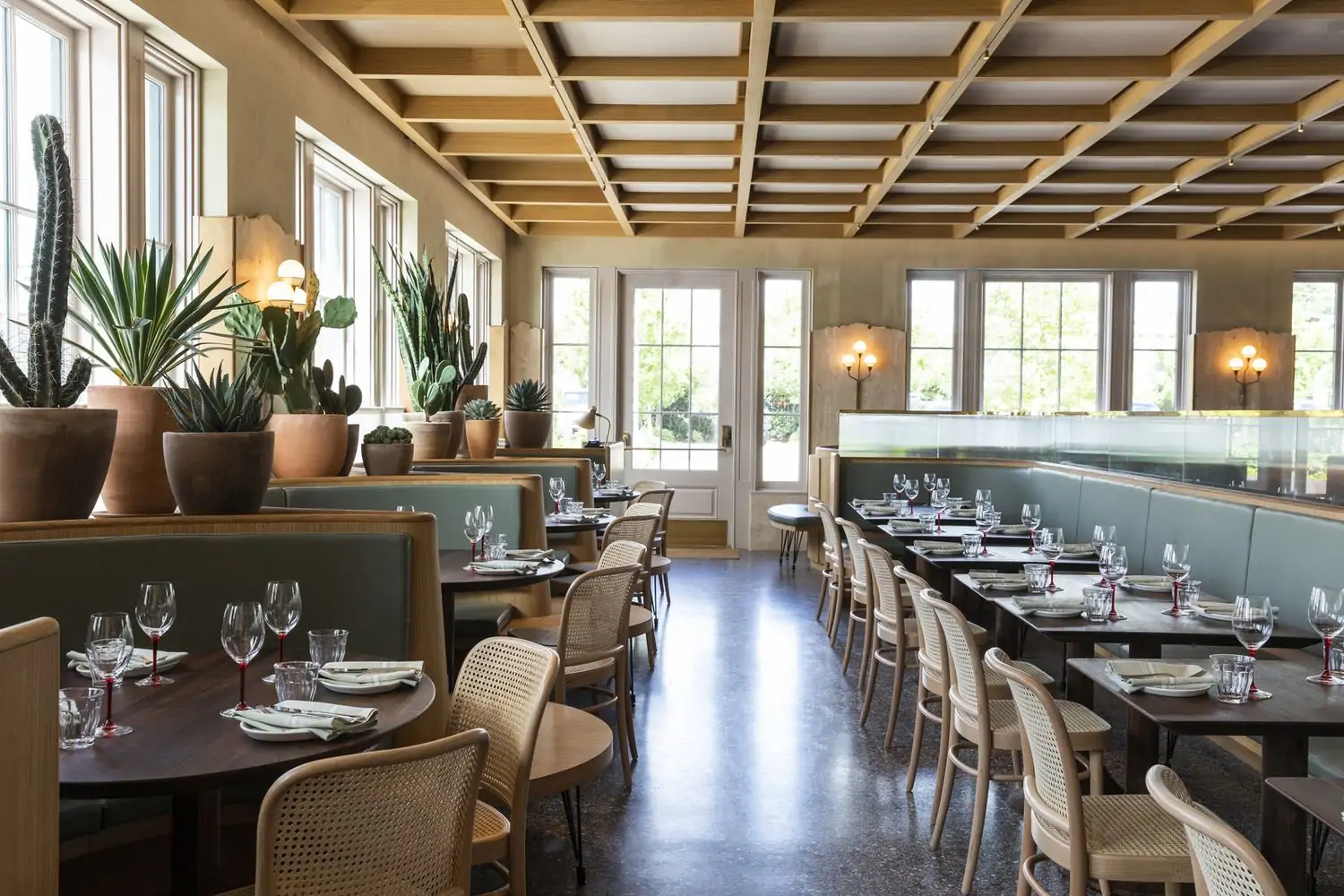 A dining room with dark marble floors and light wood furnishing on the ceiling, with circular booths and light green accents at Rosie Cannonball, one of the best cozy restaurants in Houston, bookable on OpenTable.