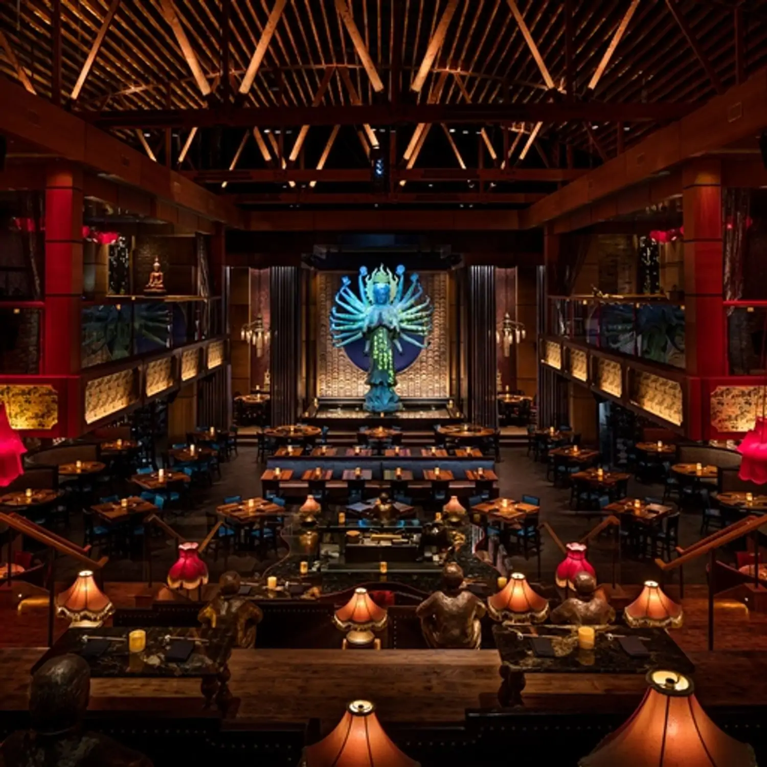 A massive two-level dining room with dark wood decor and old-fashioned lamps lighting up each table, along with a giant statue of Quan Yin watching from the front at TAO Asian Bistro, one of the best Chinese restaurants in Los Angeles found on OpenTable.