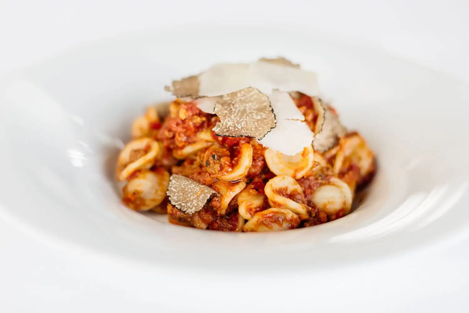 A white plate of orecchiette pasta with a rich tomato sauce, topped with shaved black truffles and grated Parmesan cheese at Craig’s, one of the best birthday restaurants Los Angeles, you can reserve on OpenTable.