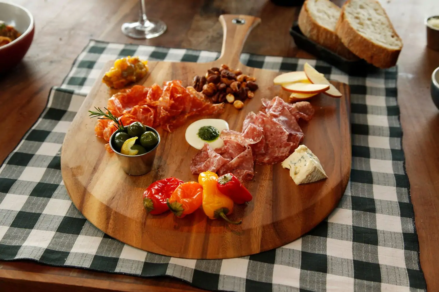 A wooden charcuterie board filled with various cured meats, cheeses, olives, nuts, fruits, and a dipping sauce atop a checkered tablecloth at North Italia, one of the best Los Angeles restaurants near LAX at OpenTable.