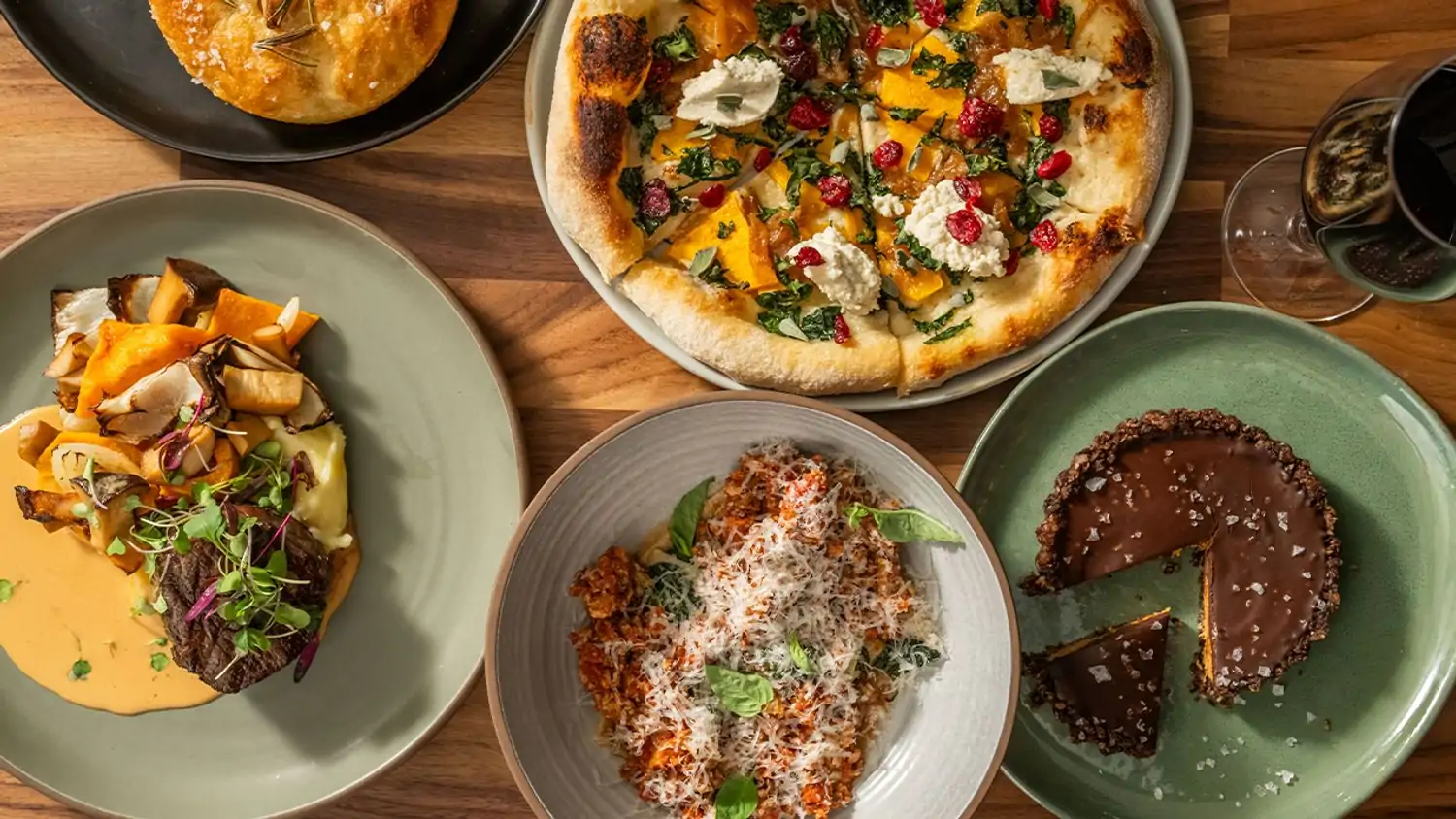 A top-down view of a variety of dishes, including pizza, pasta, roasted vegetables, a chocolate tart, and a side of bread at True Food Kitchen, one of the best Los Angeles restaurants near LAX on OpenTable.