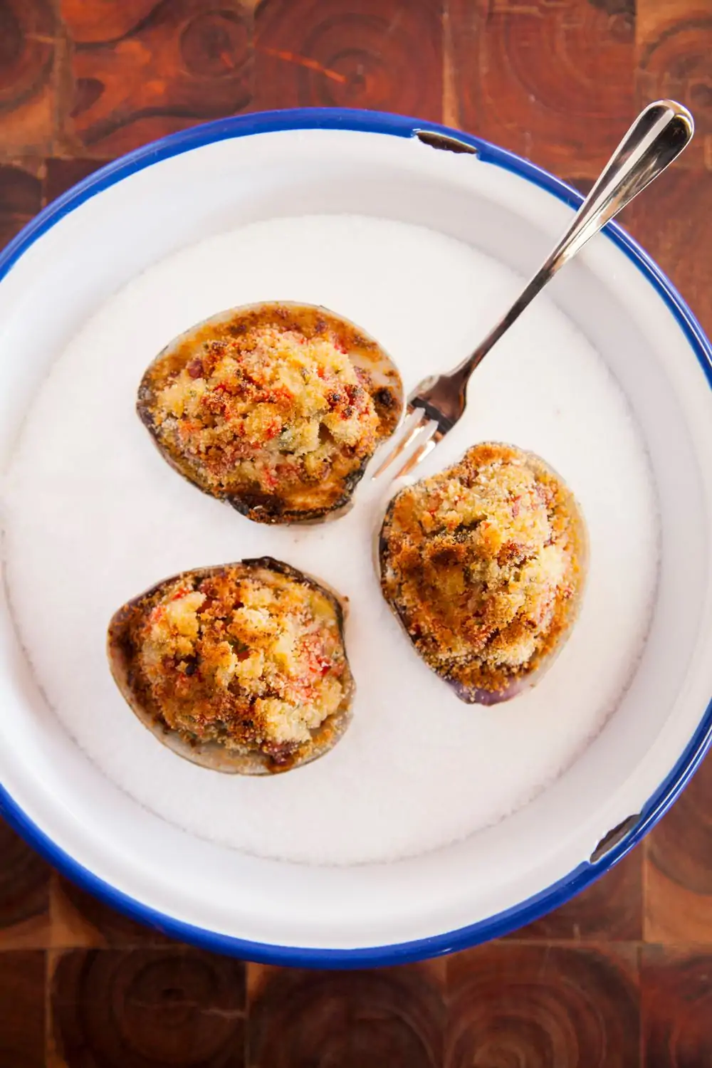 A white plate with a blue rim holds three clam shells topped with breaded clam meat at Connie and Ted’s, one of the best seafood restaurants in LA on OpenTable.