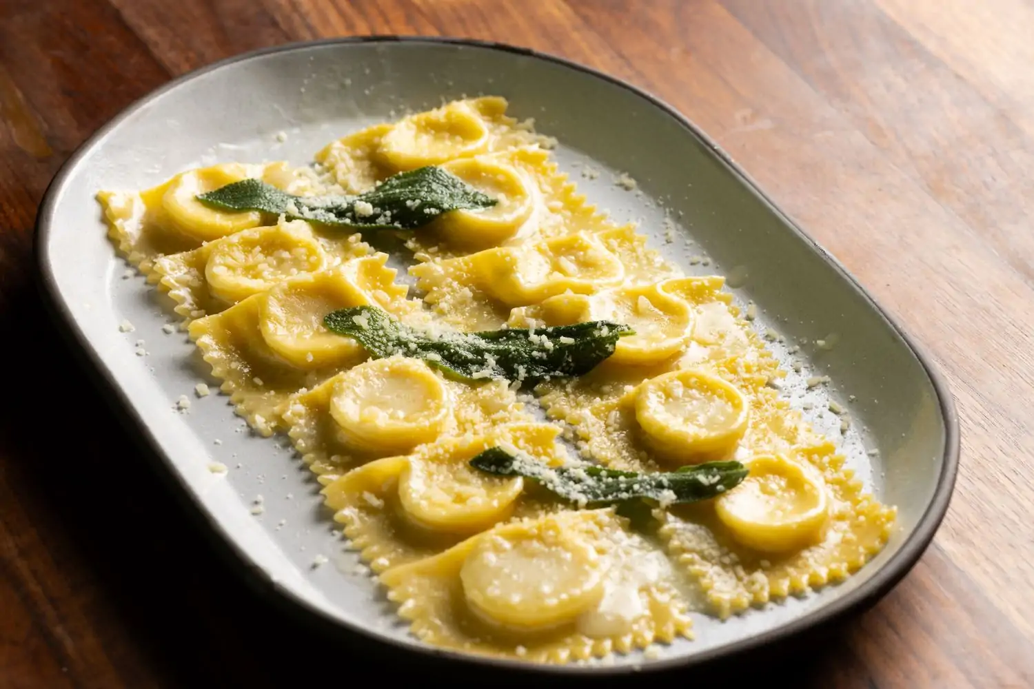 Golden ravioli are lined up in two rows of six, garnished with greenery and dusted with cheese. This dish is at OpenTable hotspot Felix Trattoria, a restaurant Venice Beach, Los Angeles.