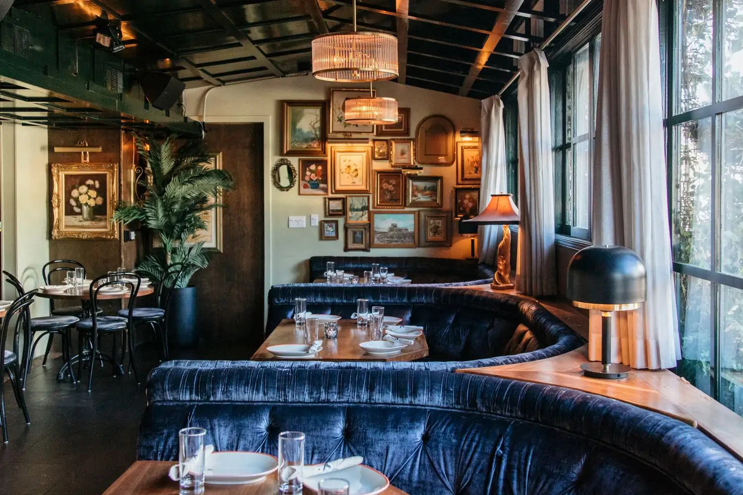 Several tables with dark sofas and paintings hanging on the wall at DiDi, one of the best birthday restaurants in Los Angeles, on OpenTable.