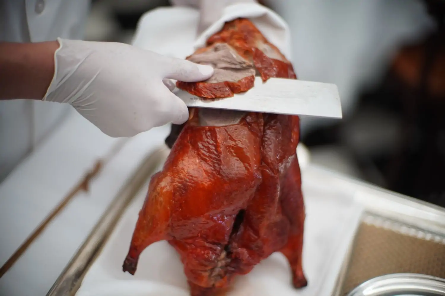 A chef holding a roasted duck and slicing pieces to be served at Mr. Chow, a world-famous Chinese restaurant in Los Angeles available via OpenTable.