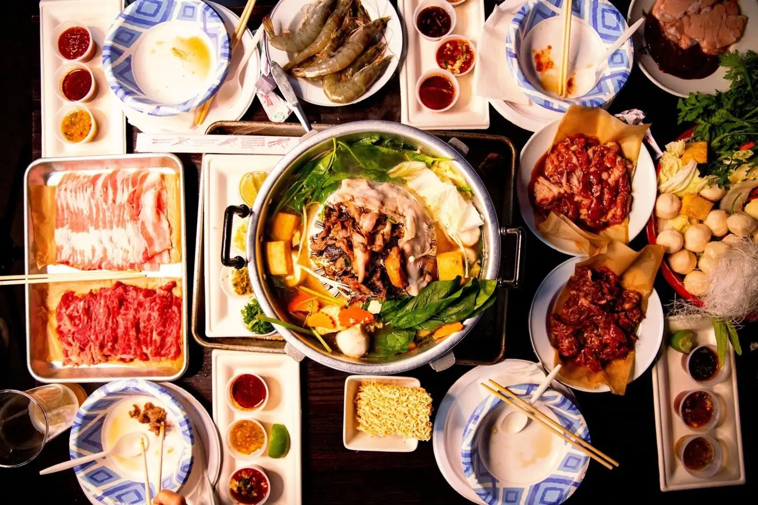 A top-down view of a table filled with a variety of Thai dishes, including grilled meats, seafood, vegetables, and dipping sauces at Ayara Thai in Los Angeles, available to book on OpenTable.