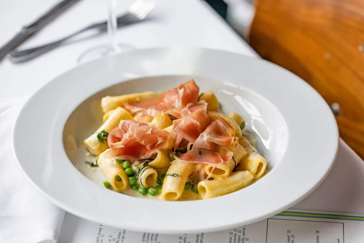 Pasta in sauce and peas topped with shaved prosciutto at one of Houston's best Italian restaurants, Coppa Osteria in Rice Village, found in OpenTable.