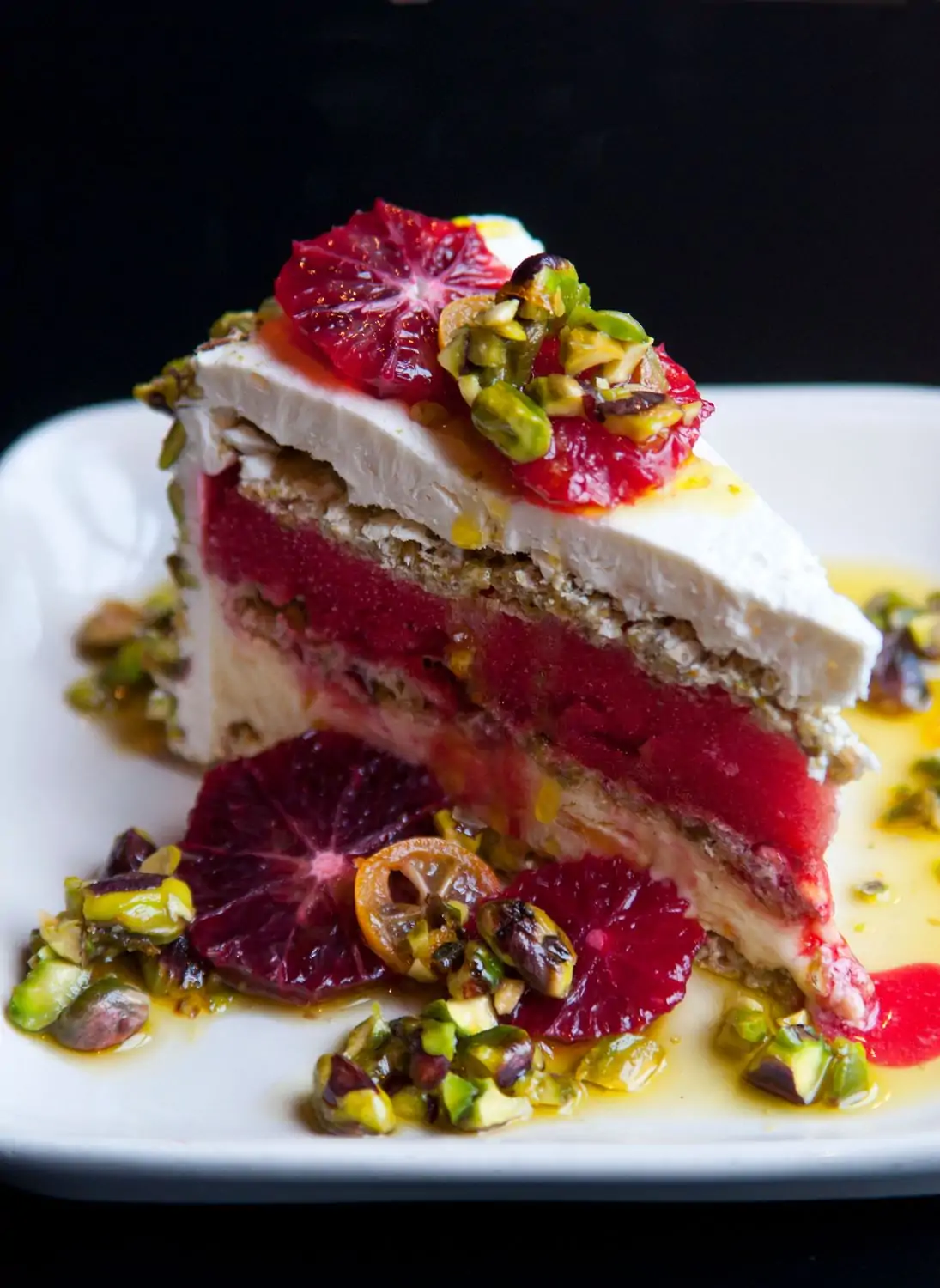A slice of layered cake with alternating pink watermelon and white cream layers. The top is garnished with blood orange slices, pistachios, and a drizzle of sauce at AOC, one of the best birthday restaurants Los Angeles, available on OpenTable.