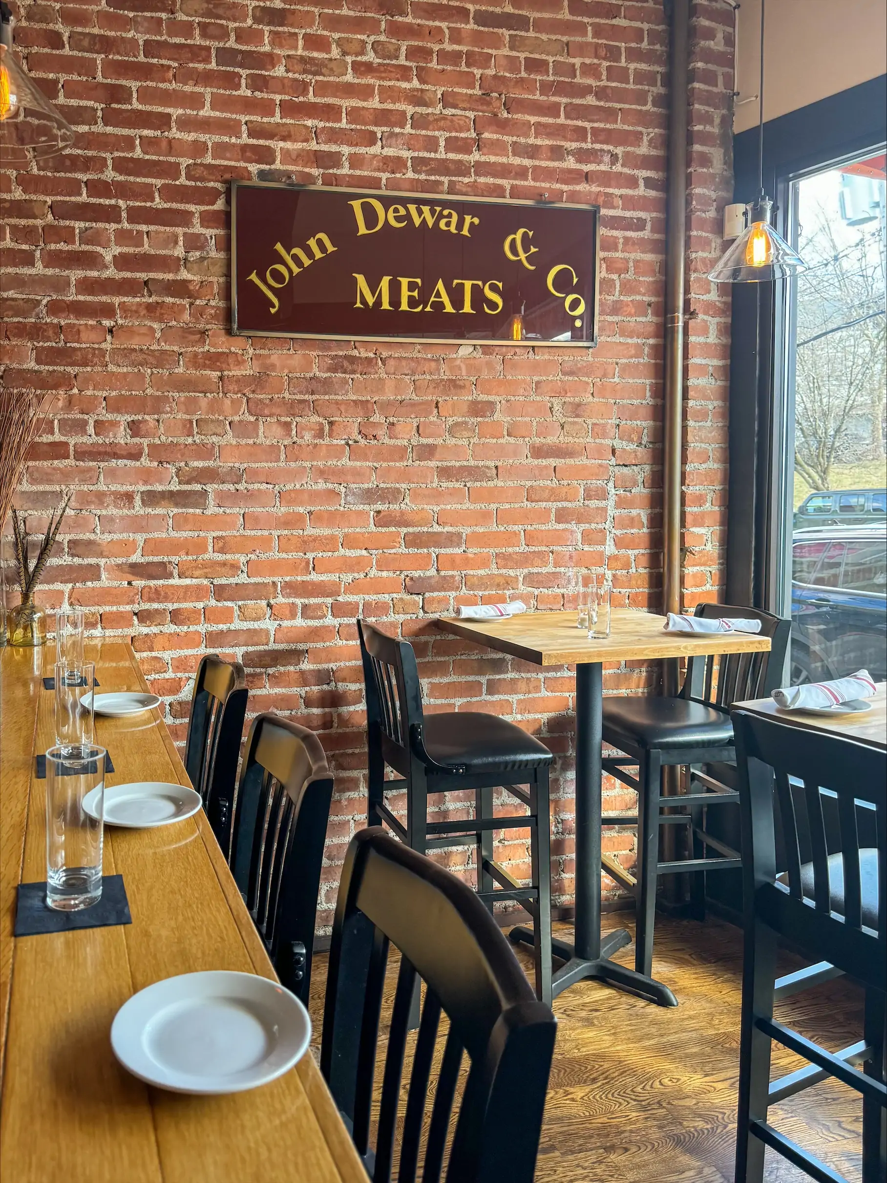 A brick-walled dining room with a wooden bar and tables at Sycamore in Boston. Book on OpenTable.