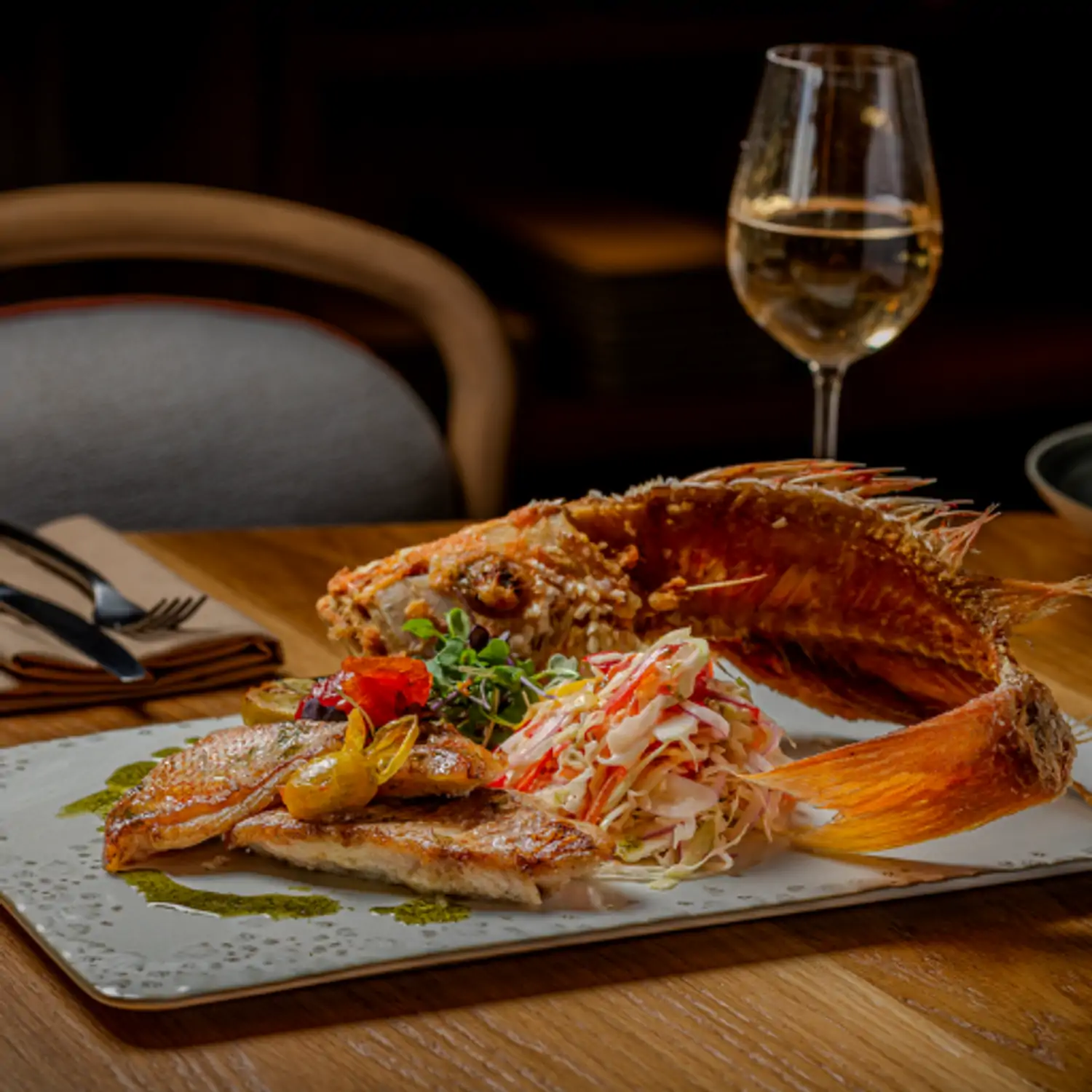 A rectangular platter with a whole fried fish, a side salad, and garnishes at Elia, a restaurant in Miami available via OpenTable.