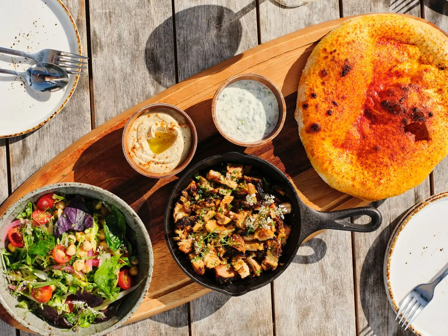 On a table in the sun, fresh salad, savory cooked dishes with spices and cheeses, and small pots of creamy sauces entice at Paloma, an OpenTable restaurant and one of the best in Venice Beach, Los Angeles.
