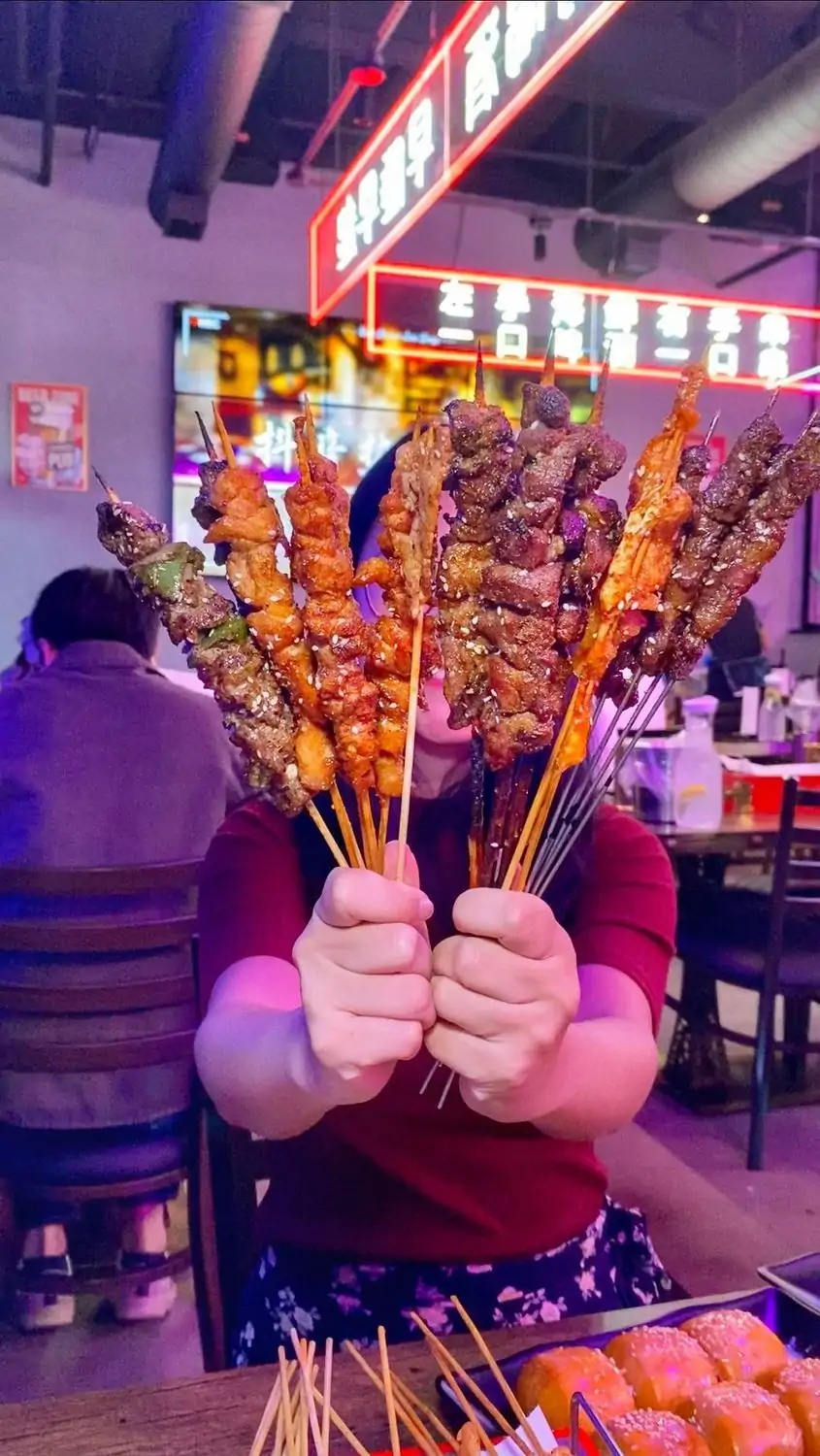 A person sitting in the dining room holding up a variety of skewers featuring grilled meat and veggies at Gao’s BBQ & Crab, a Chinese restaurant in Los Angeles that you can find on OpenTable.