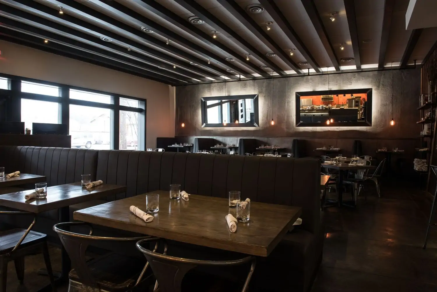 Black leather booths and wooden tables in the dining room at Stock & Barrel, one of the best cozy restaurants in Dallas, on OpenTable.