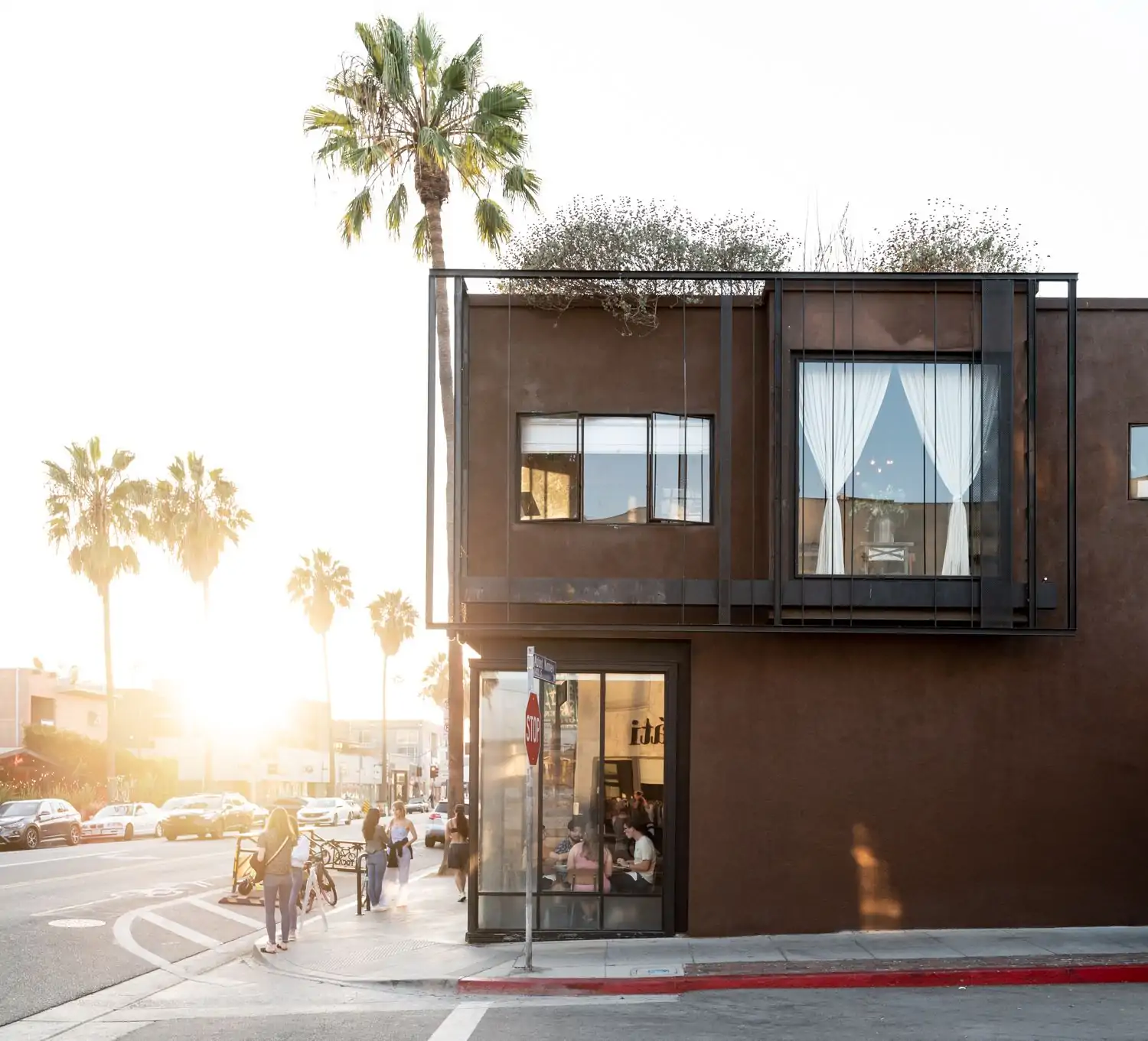 On a corner of palm-tree-lined city streets, diners are visible through the floor-to-ceiling windows socializing at Gjelina, an OpenTable restaurant in Venice Beach, Los Angeles.
