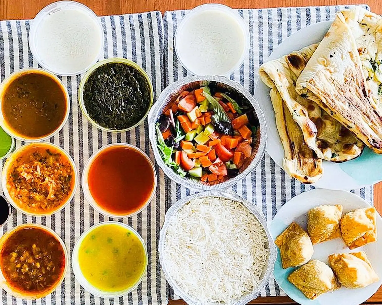 To-go dishes featuring Indian thali classics, including naan, rice, samosas, dhal, chicken curry, and palak at Indian House, a restaurant on OpenTable.
