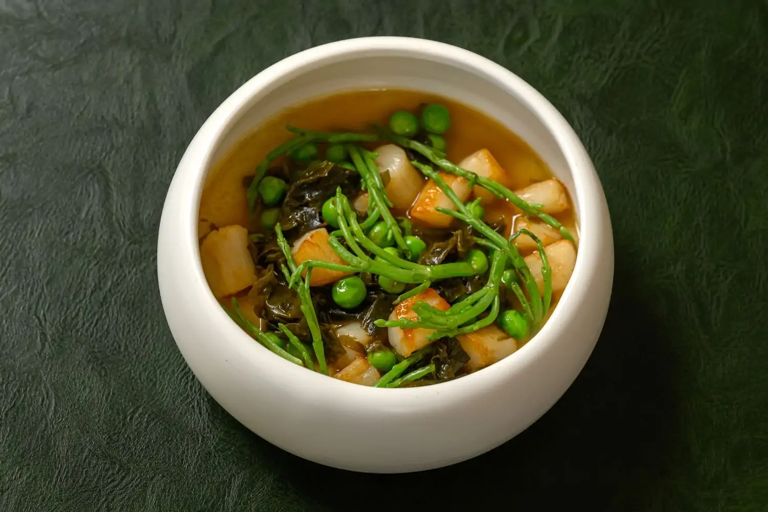 A ceramic bowl with steamed egg custard with scallops, peas, and sea lettuce at Firstborn in LA. Book on OpenTable.