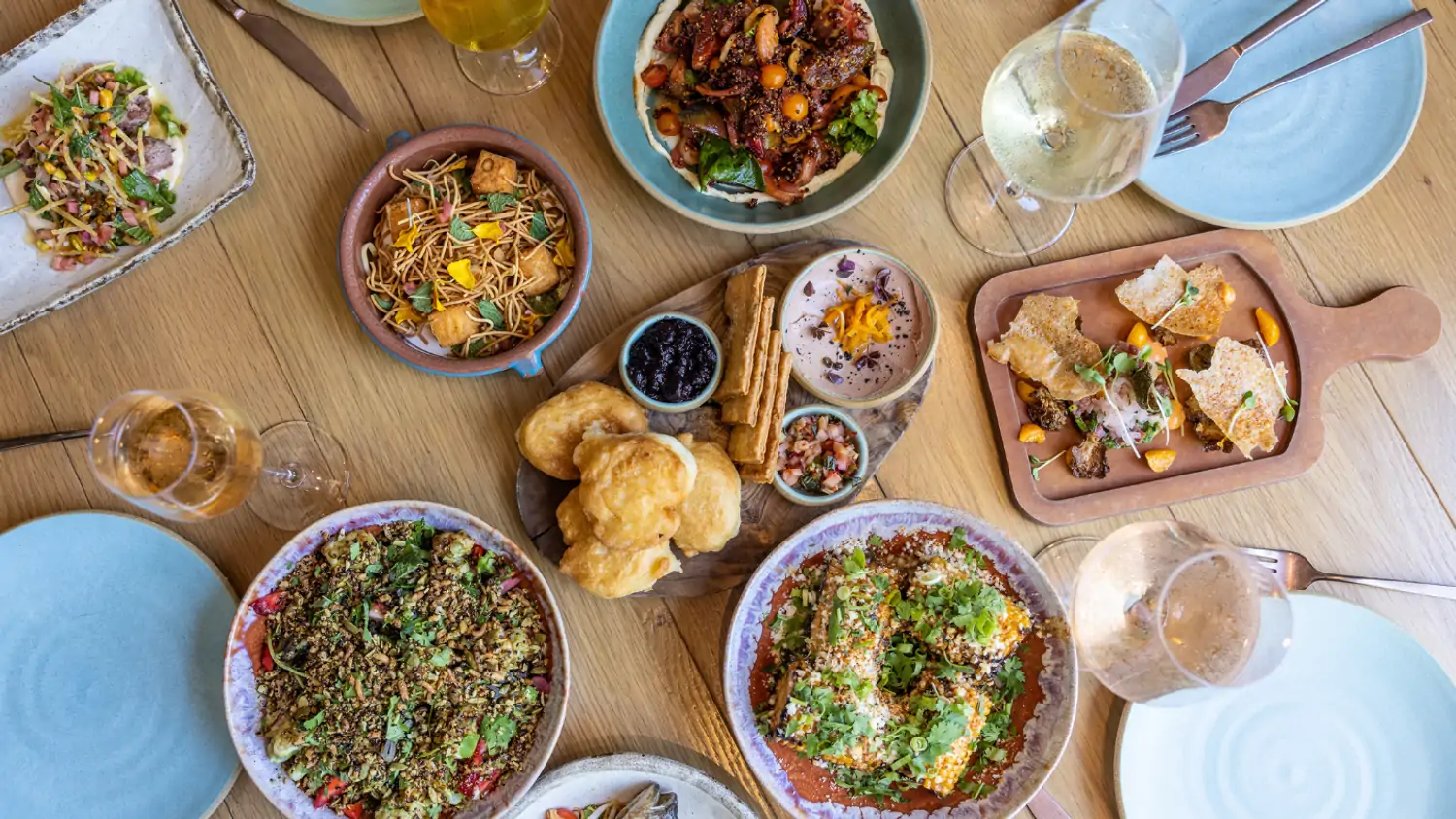 Blue and white plates with global dishes like crackers and chutney, goat empanadas, and plantain cake at Valley Goat in Sunnyvale, one of the best new restaurants in San Francisco. Book on OpenTable.